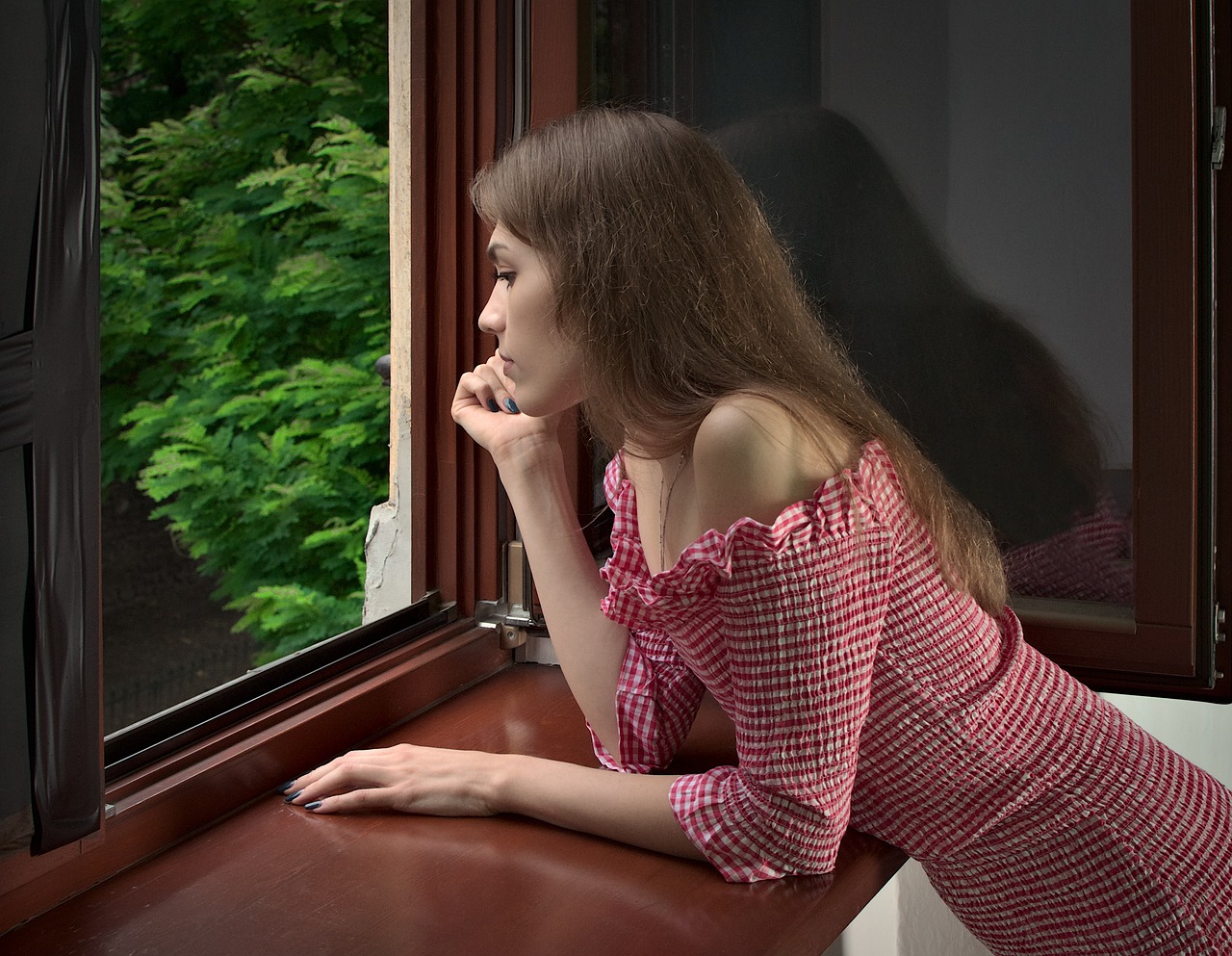 Mujer joven asomada a la ventana | Foto: Pixabay