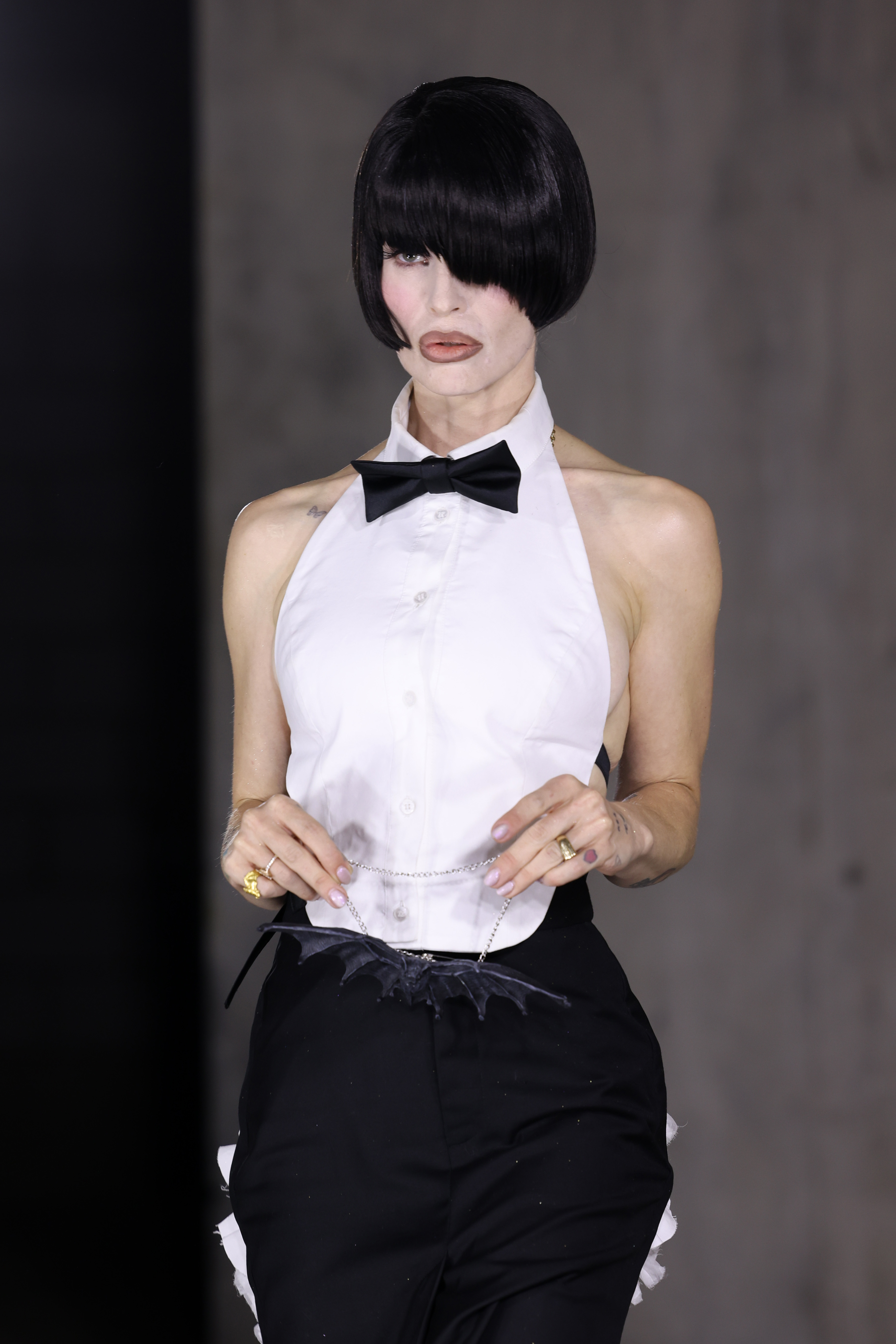Kelly Osbourne lució un nuevo y llamativo look con un corte bob negro azabache que le tapaba un ojo, combinándolo con una camiseta blanca de tirantes, un moño negro y unos pantalones de sastrería, además de un accesorio con forma de murciélago que recordaba el famoso legado rockero de su padre, Ozzy. | Fuente: Getty Images.