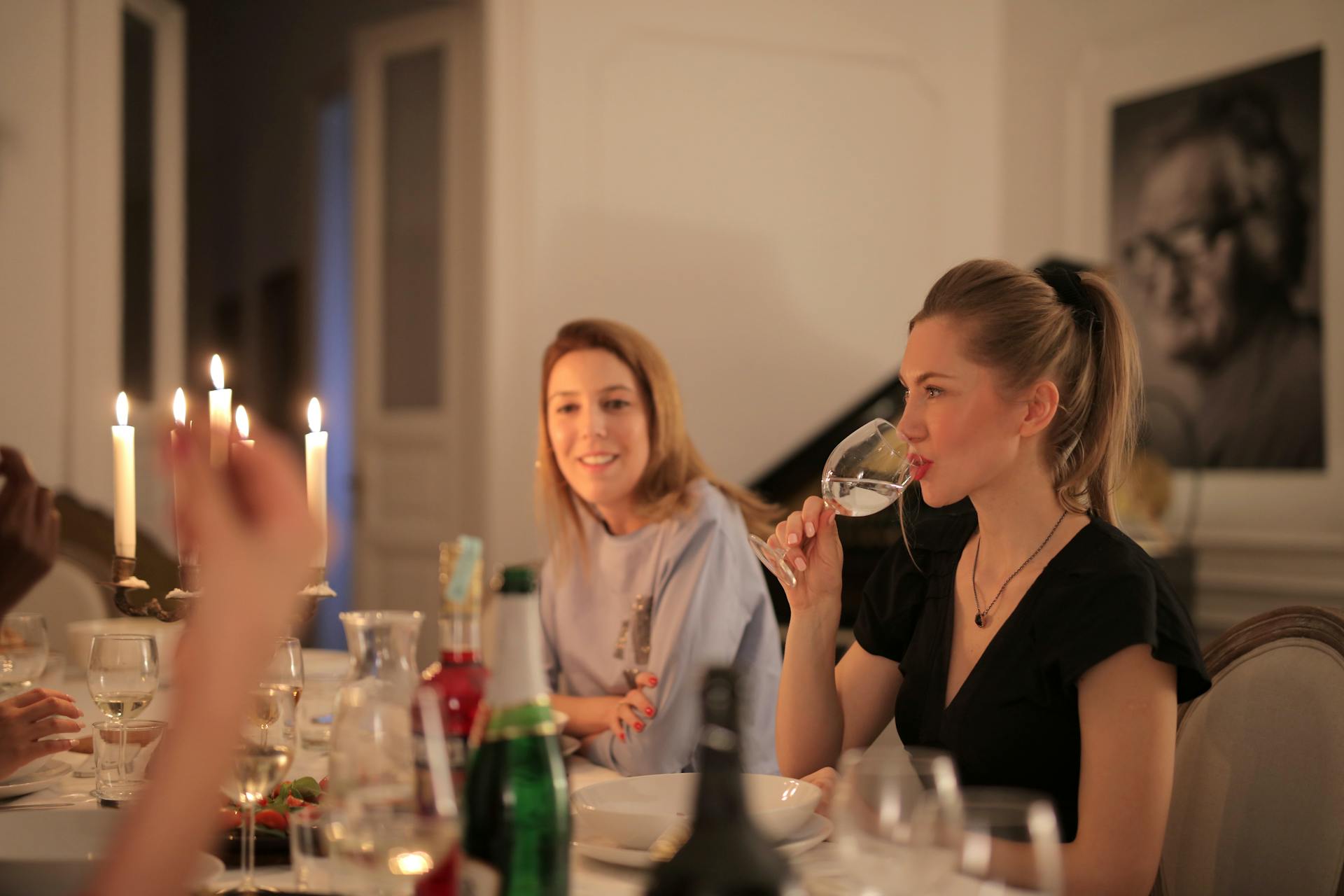 Una mujer bebiendo vino mientras cena con sus amigos | Fuente: Pexels