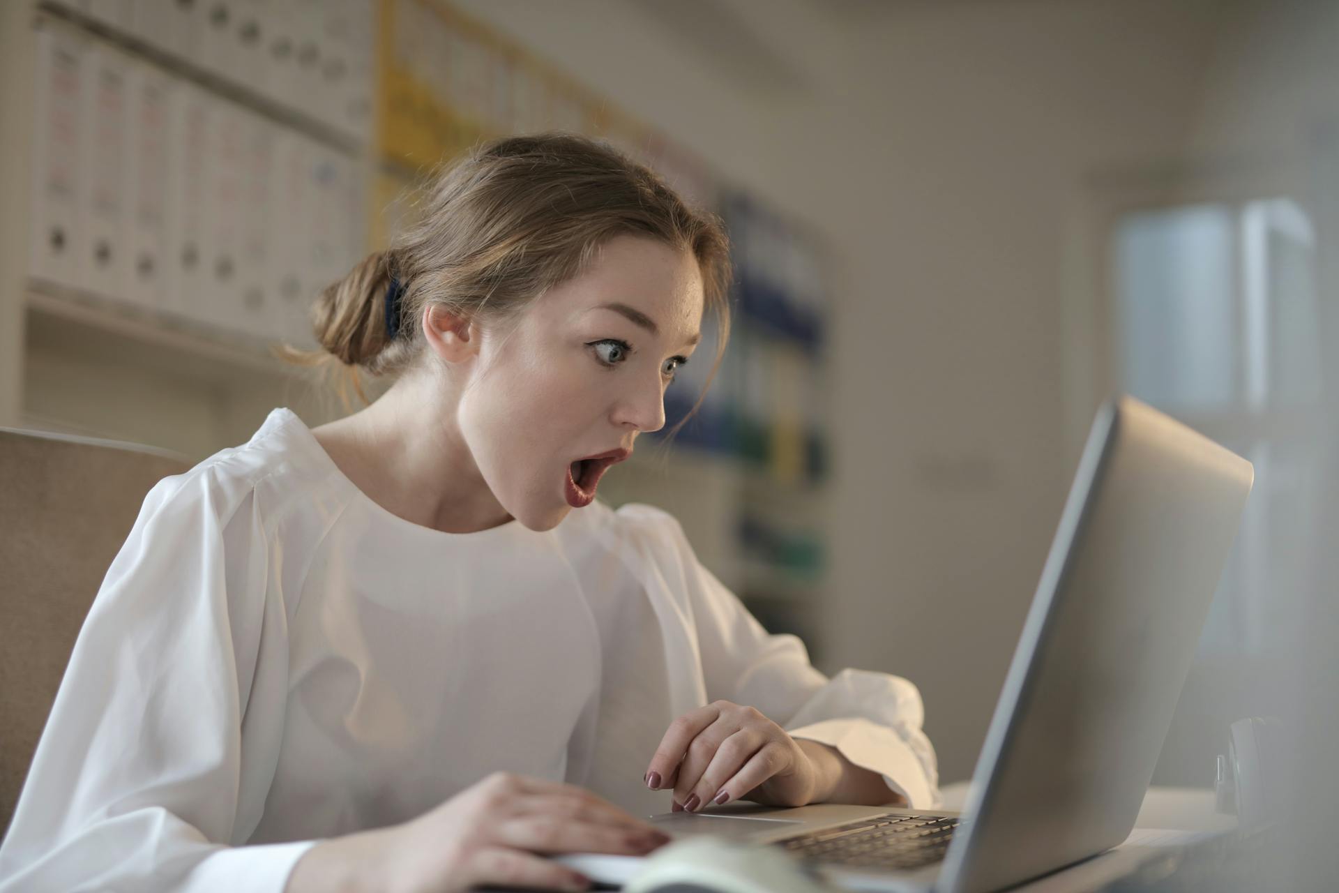 Una mujer en estado de shock mientras mira la pantalla de un portátil | Fuente: Pexels