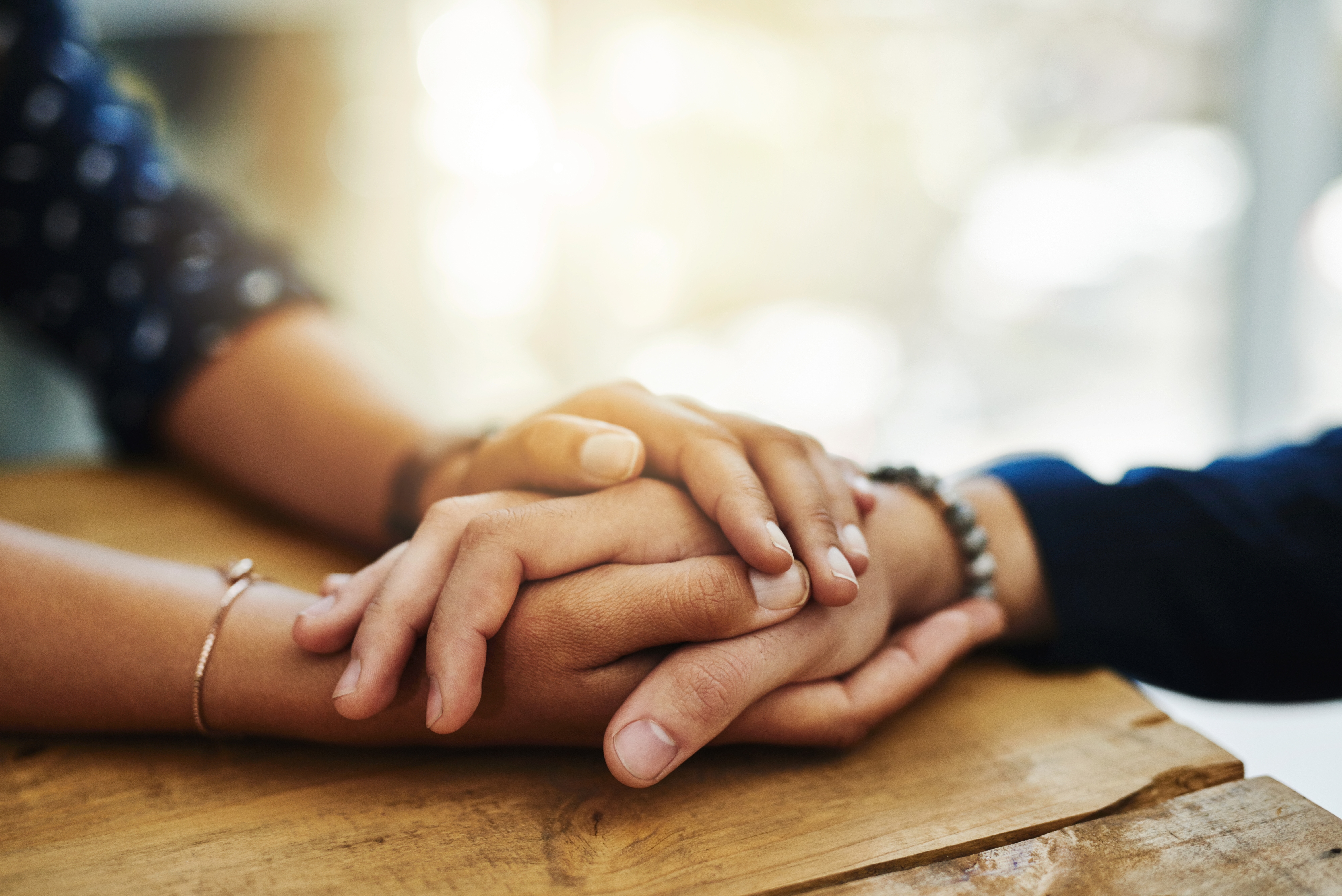 Un hombre y una mujer toman sus manos sobre una mesa | Fuente: Shutterstock