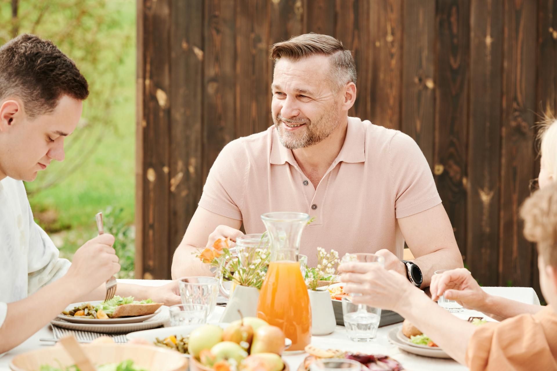 Un hombre sonriente en la mesa con su familia | Fuente: Pexels