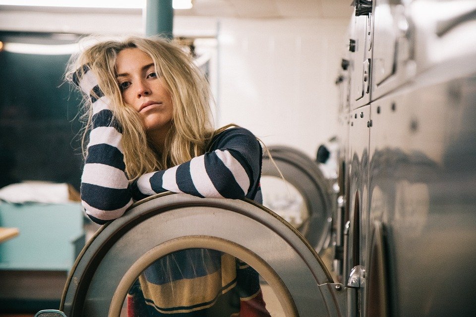 Mujer apoyada sobre la puerta de una lavadora. | Foto: Pixabay