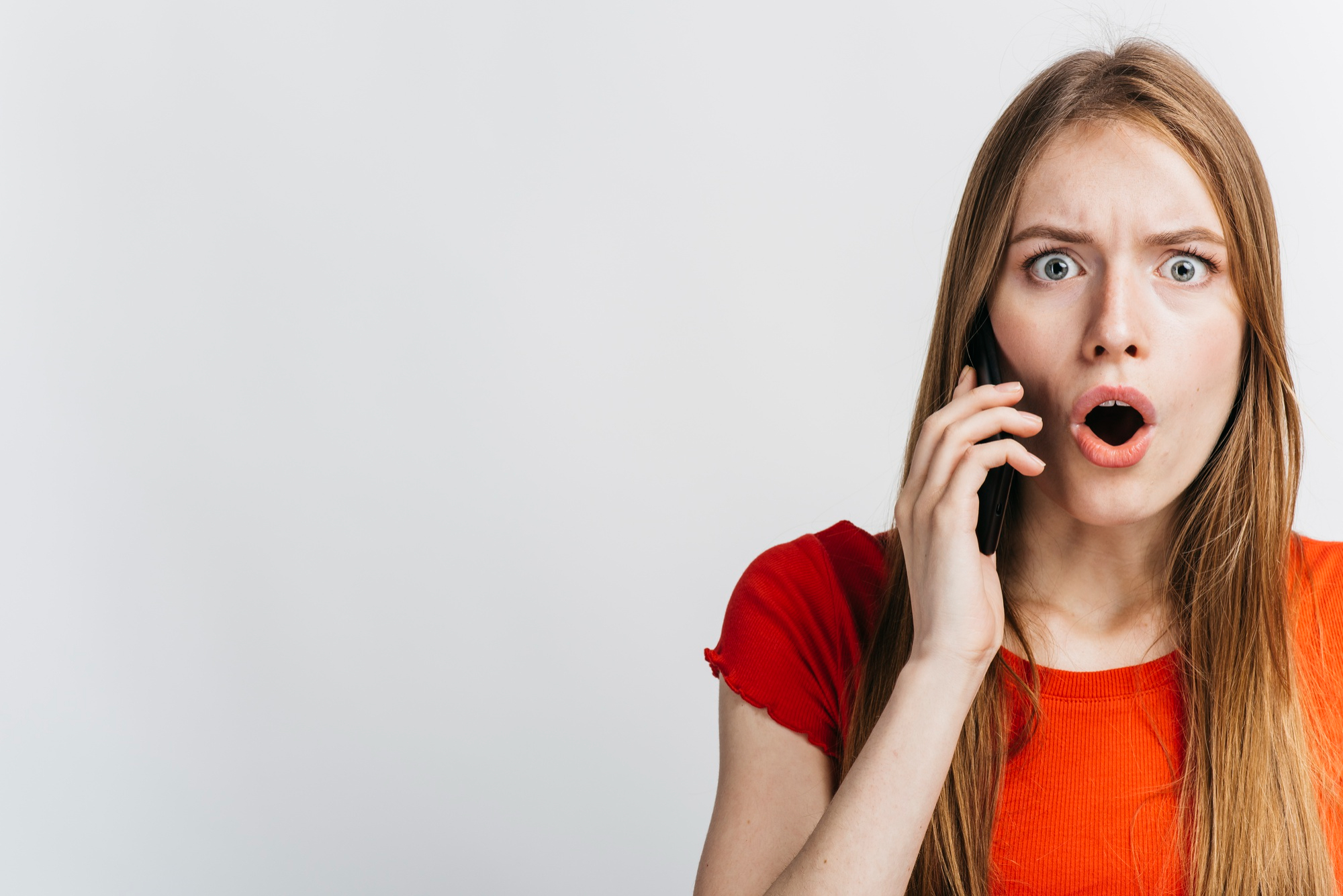 Una mujer reacciona en estado de shock durante una llamada telefónica | Fuente: Freepik
