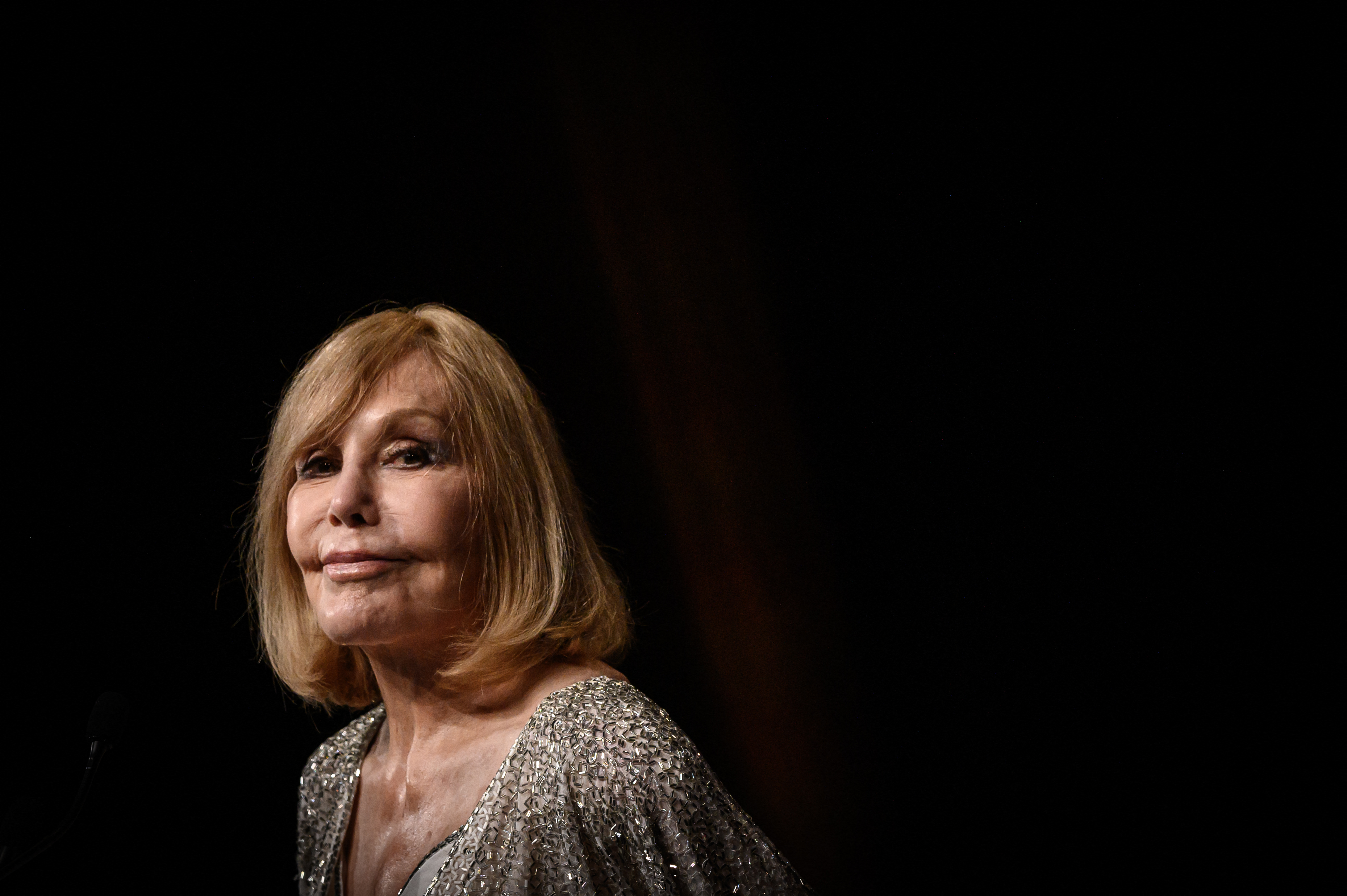 Kim Novak pronuncia un discurso antes de recibir el Premio Icon por su trayectoria en la 51.ª edición del Festival de Cine Americano de Deauville, en Francia, el 6 de septiembre de 2025. Lleva un conjunto con detalles plateados mientras se dirige al público con un fondo oscuro en el escenario. | Fuente: Getty Images