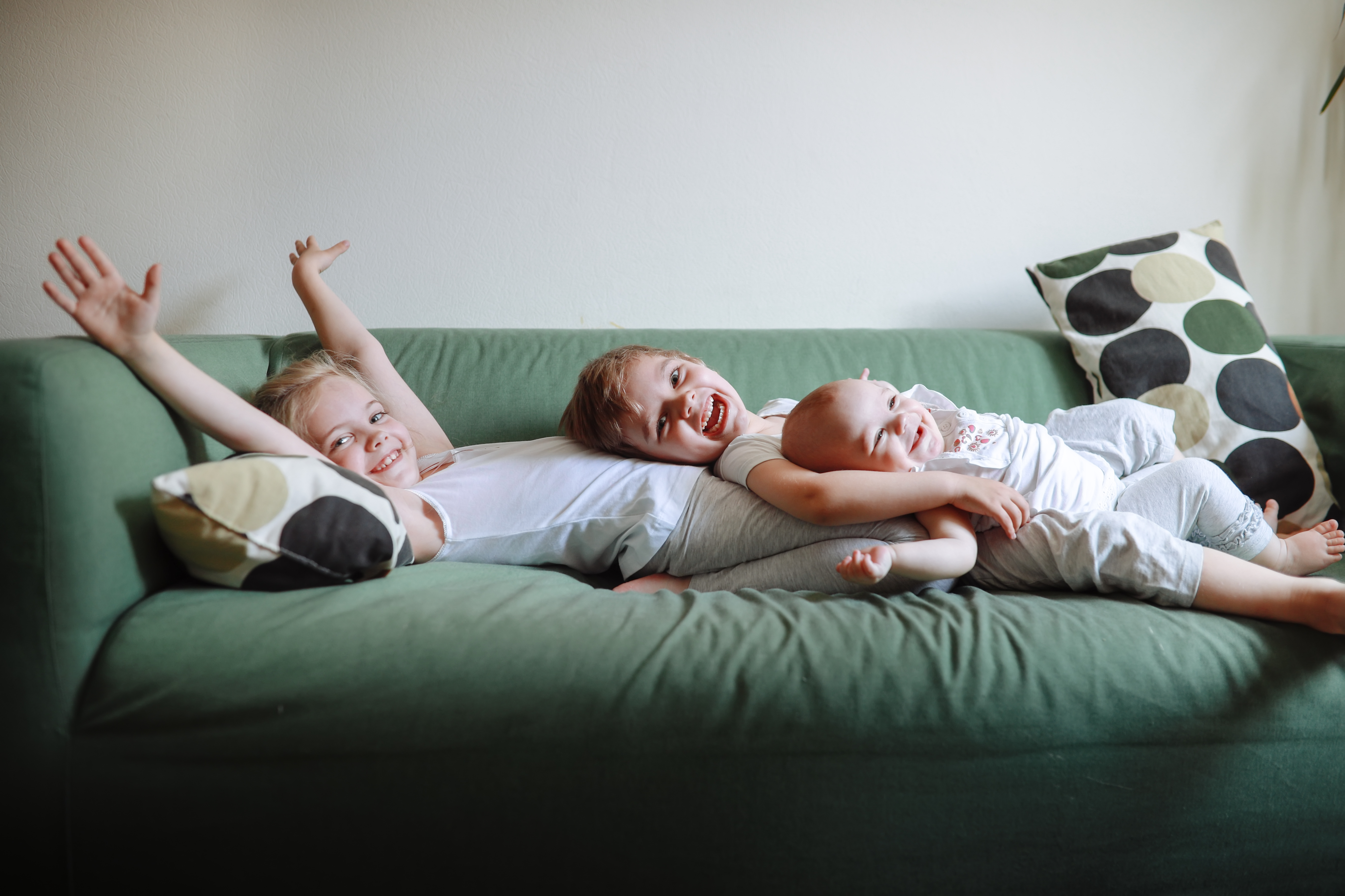 Tres hermanos felices tumbados en un sofá | Foto: Getty Images