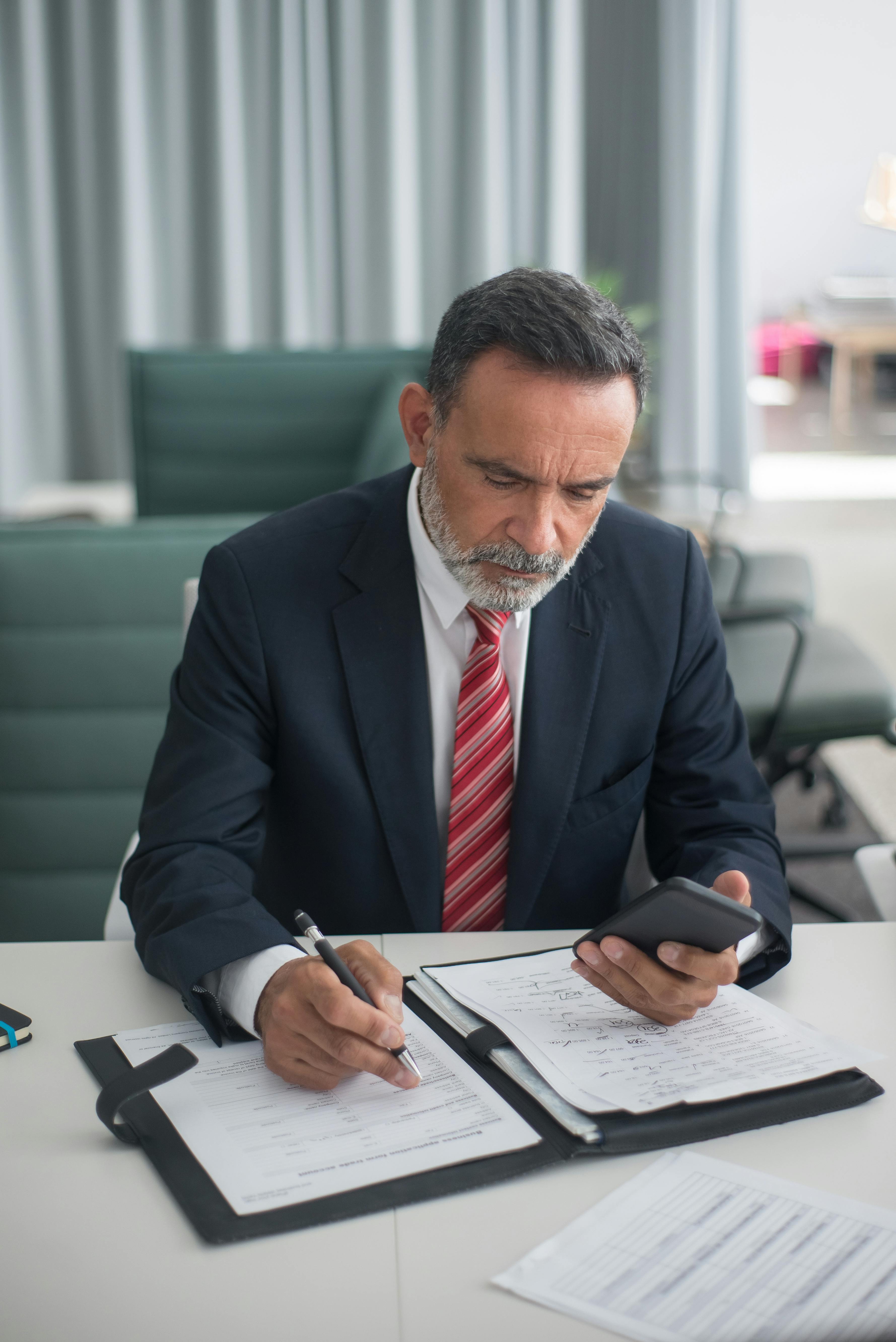 Un uomo con il cellulare in mano mentre scrive qualcosa | Fonte: Pexels