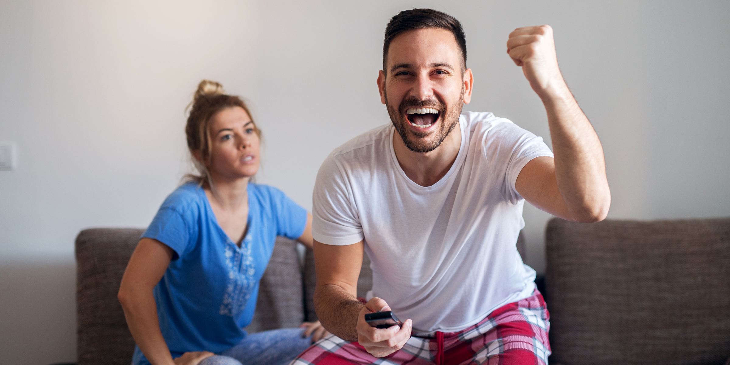 Una mujer mira a su marido mientras éste ve la tele | Fuente: Shutterstock