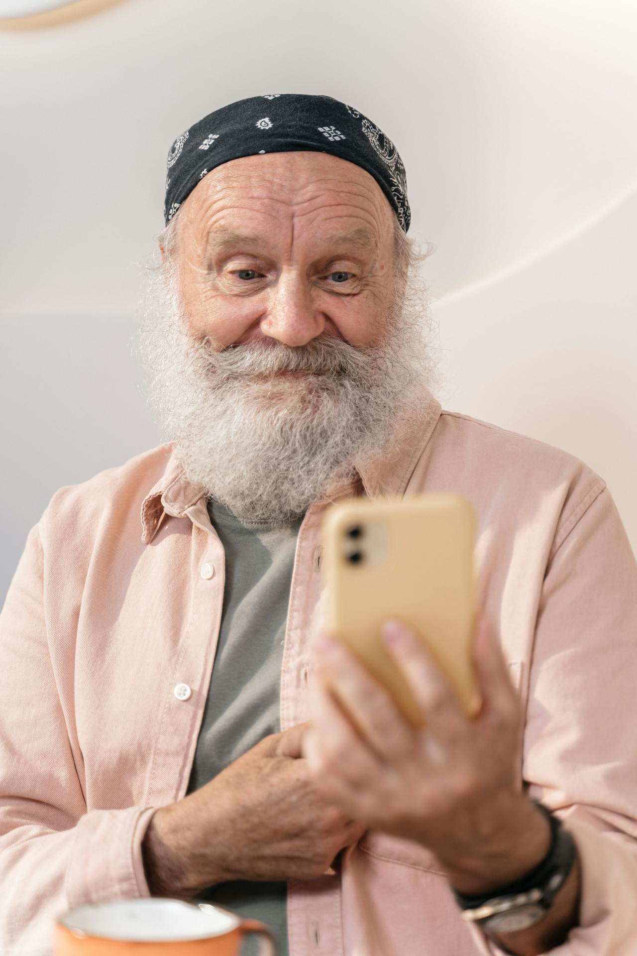 Un hombre mayor mirando su teléfono y sonriendo | Fuente: Pexels