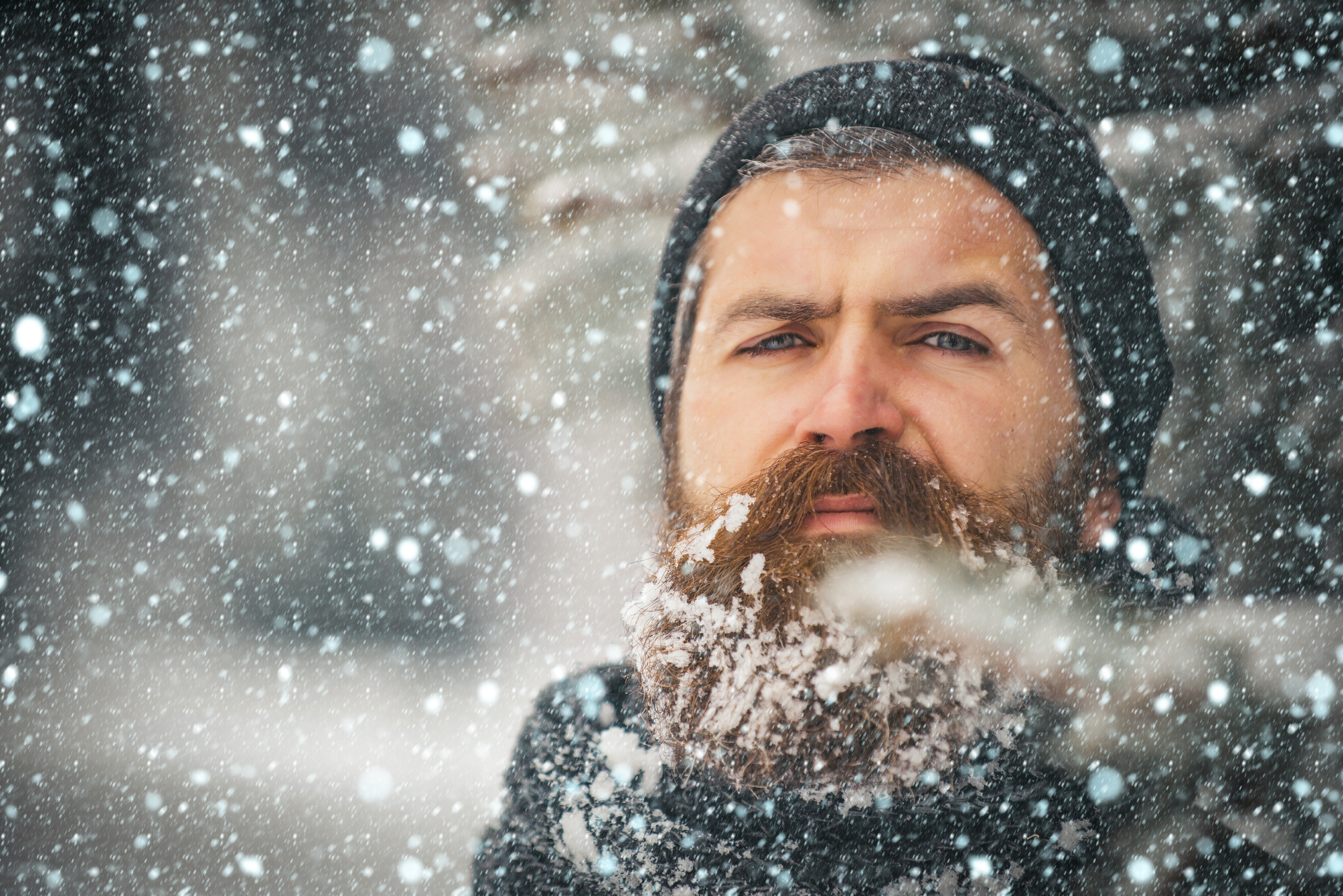 Un hombre con barba y sombrero, de pie al aire libre mientras cae la nieve. | Foto: Shutterstock