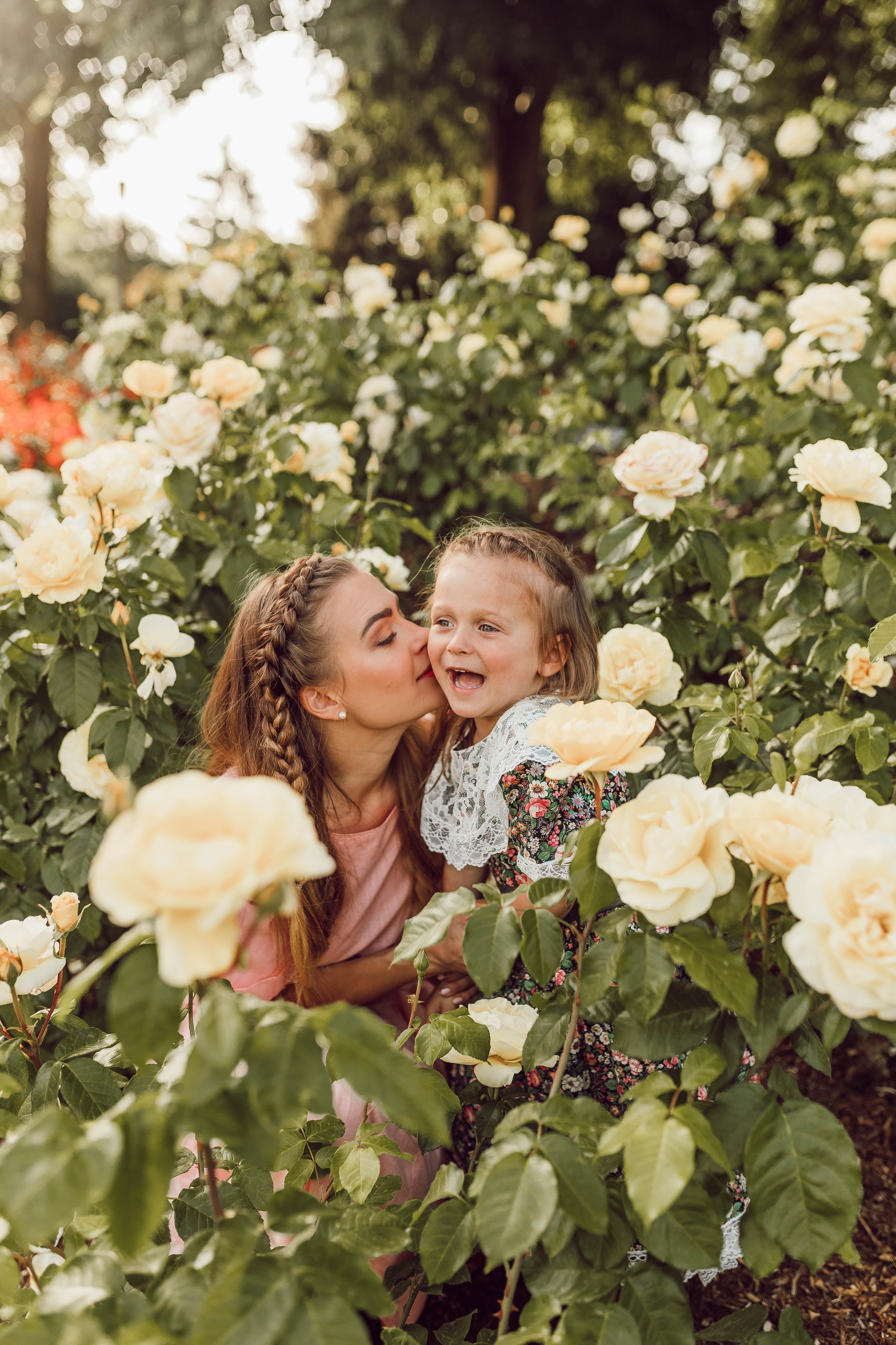 Mujer besa a niña pequeña en un campo de flores | Foto: Unsplash
