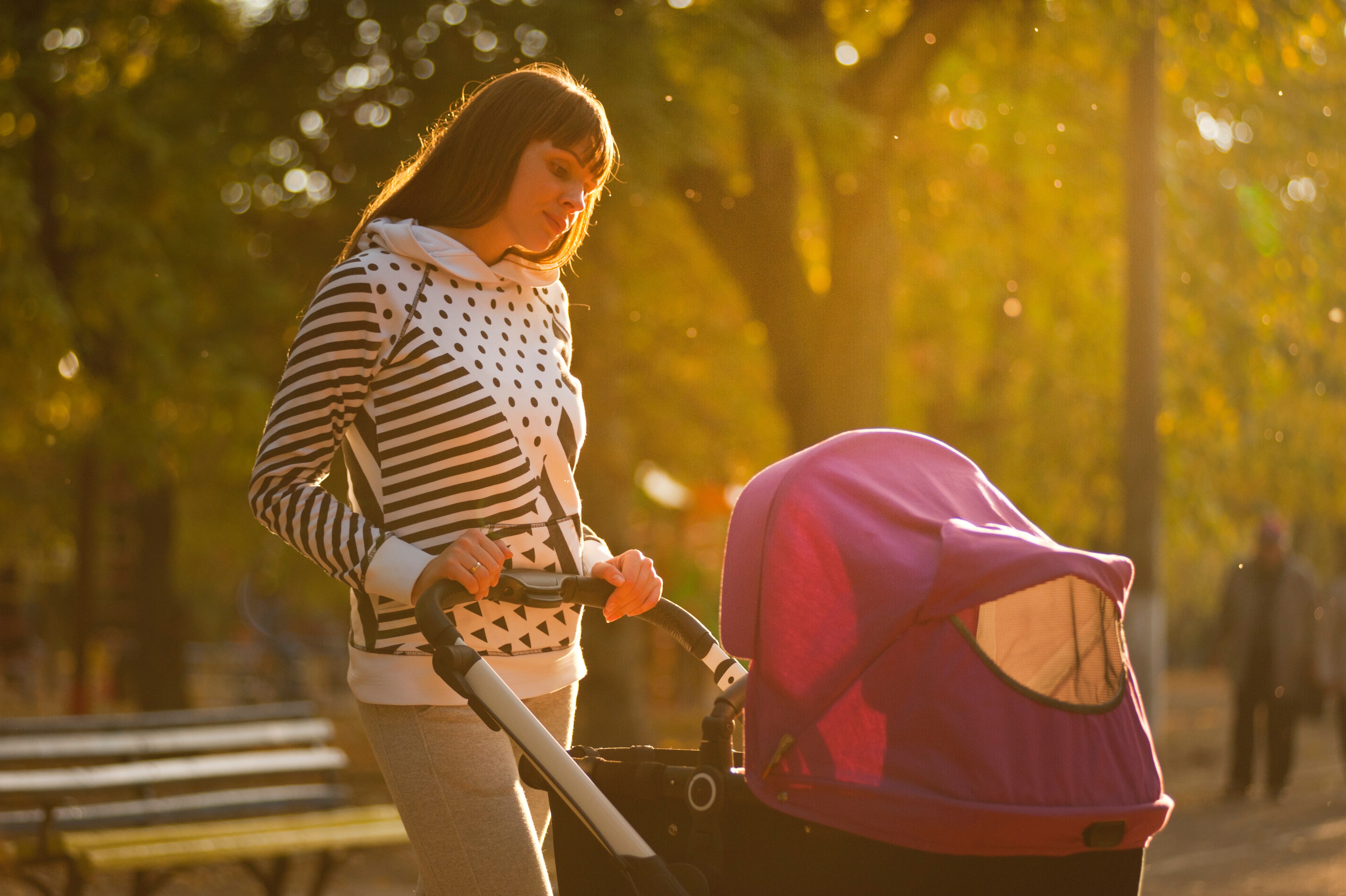 Una mujer empujando un cochecito de bebé en un parque. | Foto: Pexels