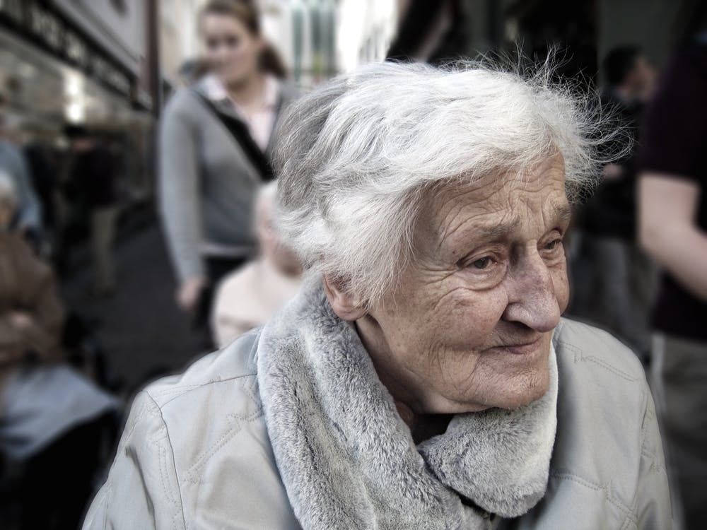 Anciana cerca de otras personas en la calle. | Foto: Pexels
