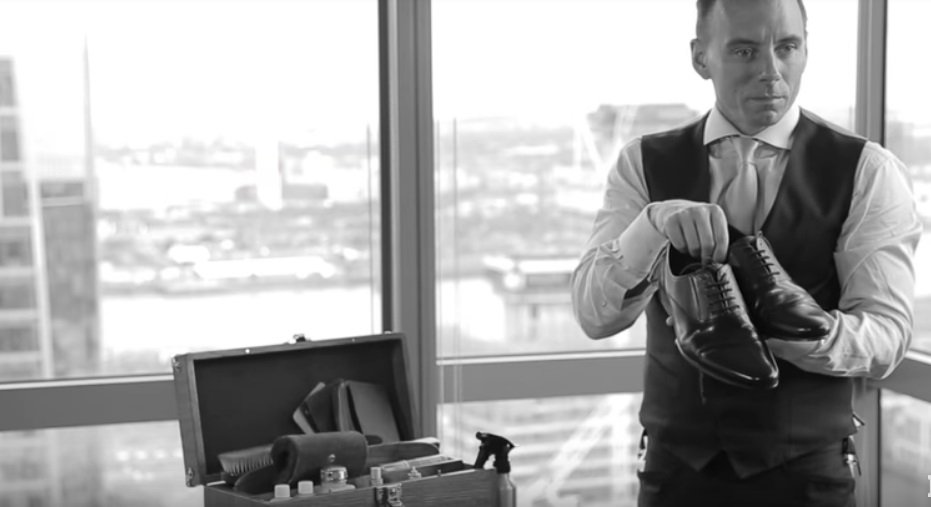 Drew Goodall muestra zapatos que acaba de lustrar en su oficina | Foto: YouTube/IBTimes UK