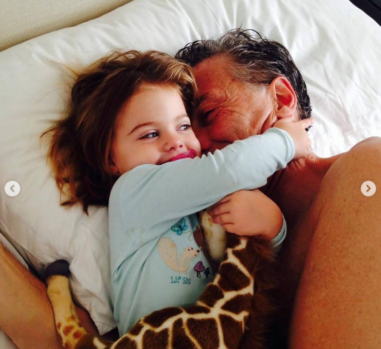 Mauricio Macri y Antonia comparten un tierno abrazo sobre la cama. La pequeña, con pijama celeste de ardilla y abrazando una jirafa de peluche, sonríe ampliamente con su chupete mientras rodea el cuello de su padre. | Fuente: Instagram/mauriciomacri