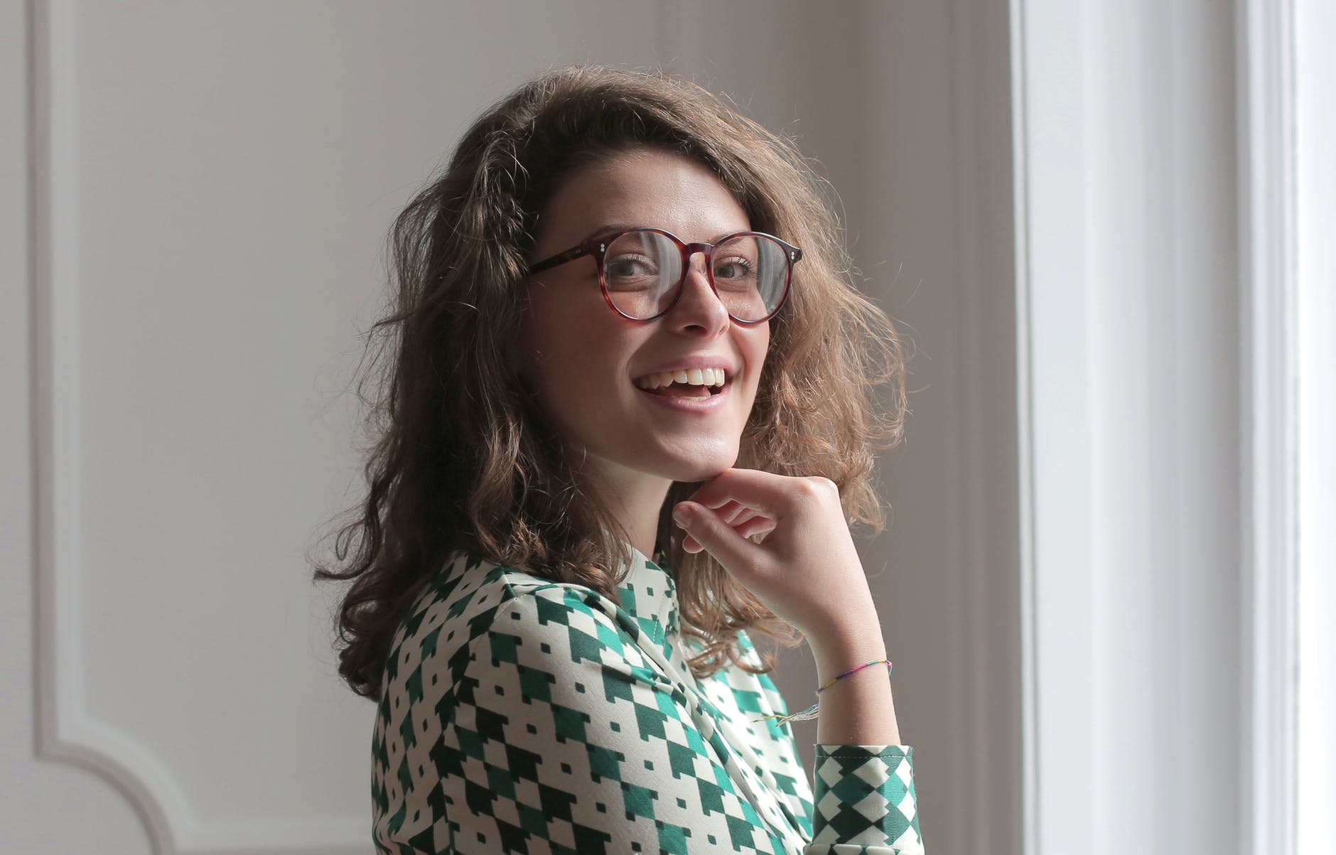 Una mujer joven con lentes sonrie. | Foto: Pexels