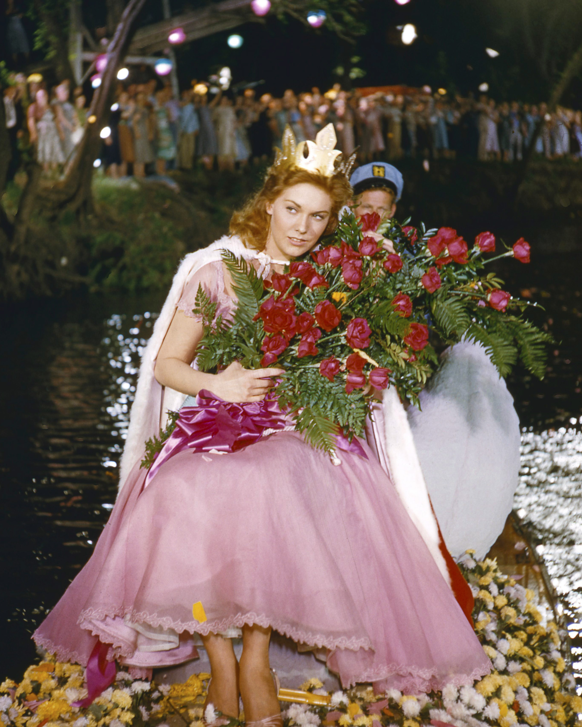 Kim Novak interpreta a Madge Owens en "Picnic", con un vestido rosa y una corona, mientras sostiene un gran ramo de flores. | Fuente: Getty Images
