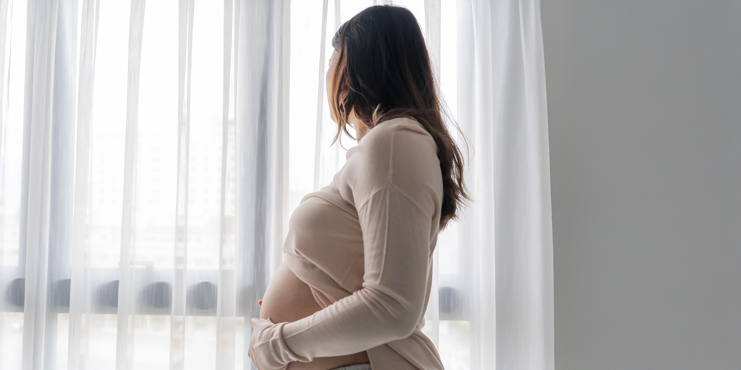 Una mujer embarazada mirando por la ventana | Fuente: Shutterstock