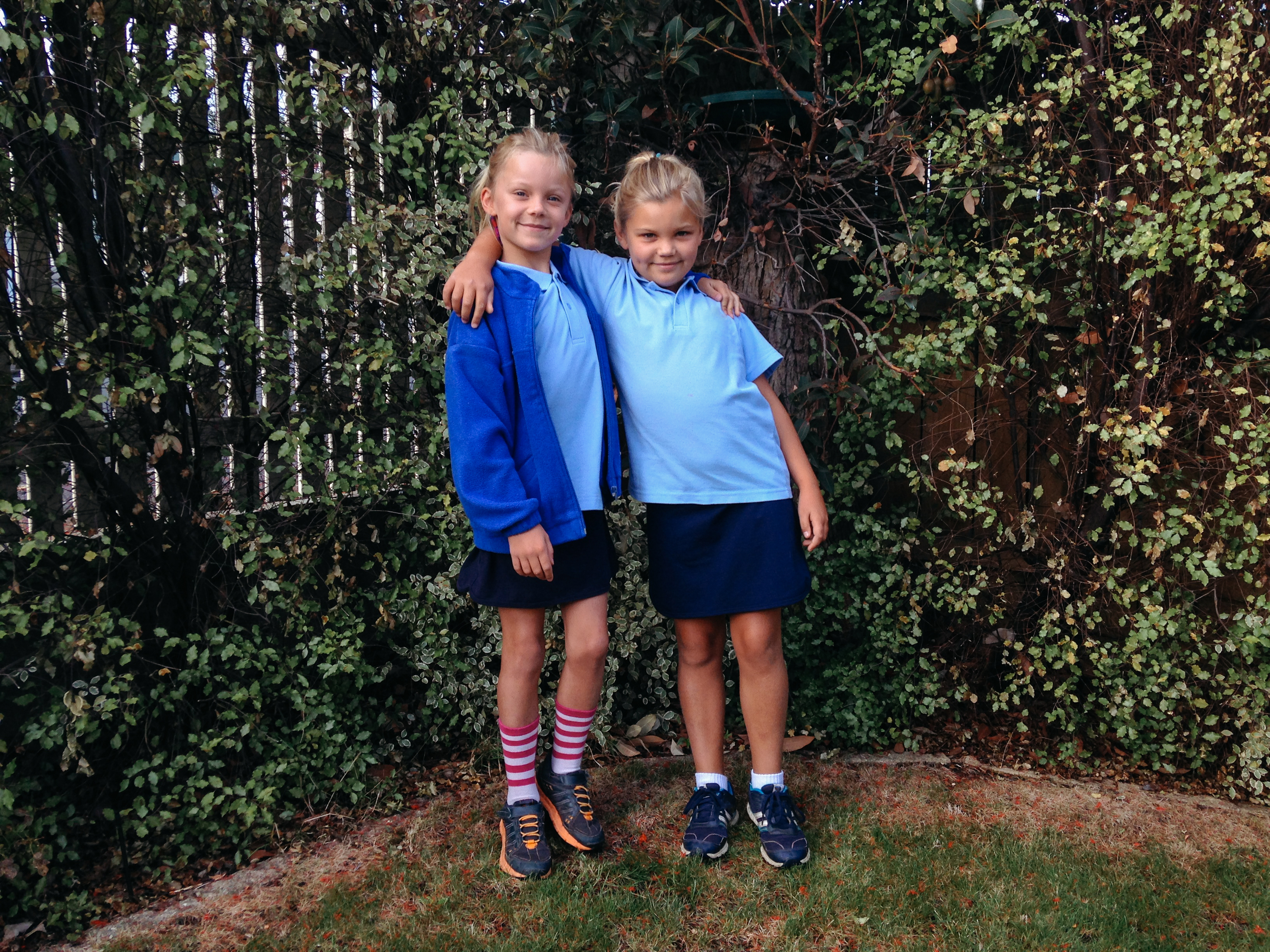 Dos hermanas vestidas con uniformes escolares permanecen juntas abrazadas. | Foto: Getty Images