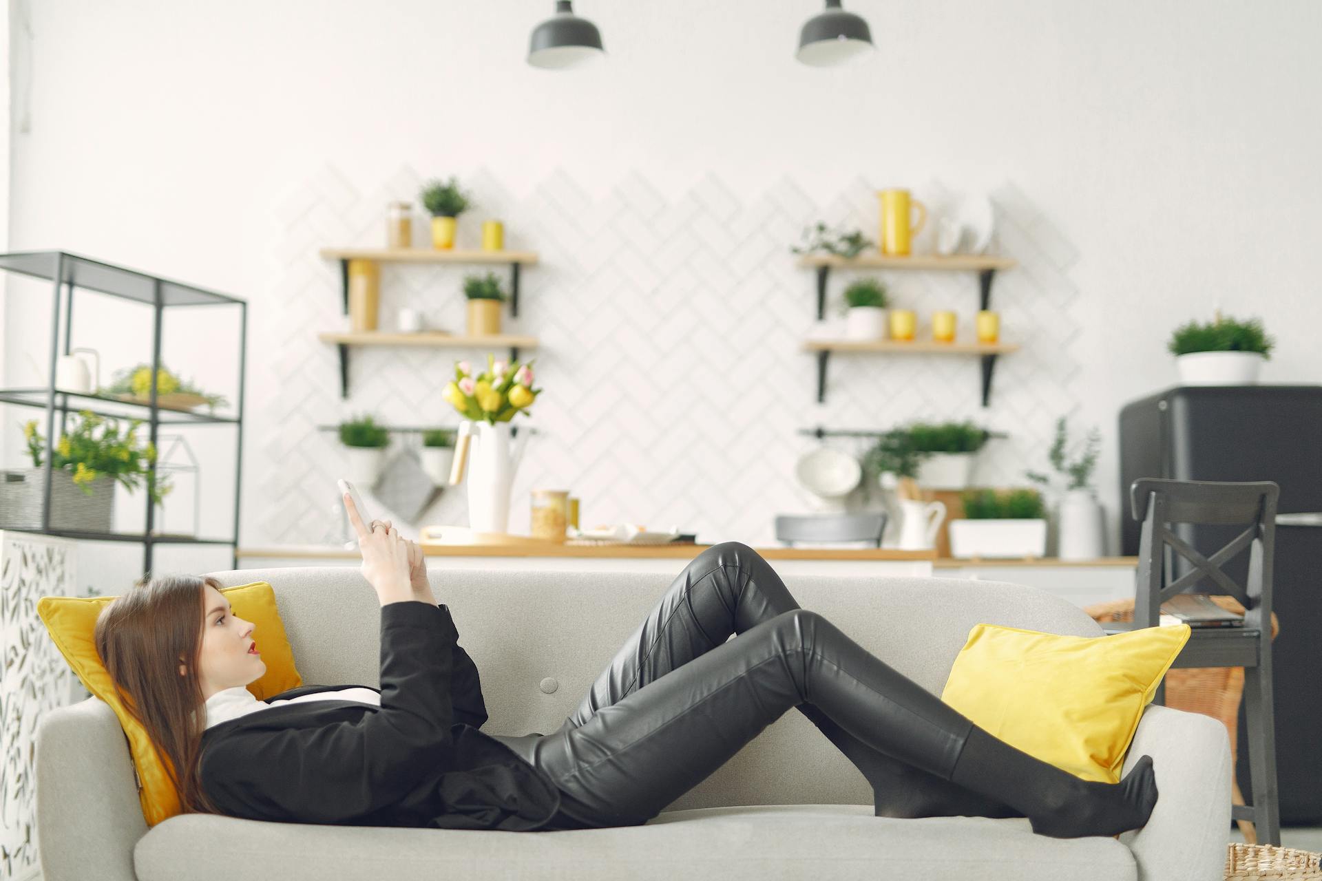 Una mujer tumbada en el sofá y utilizando su teléfono | Fuente: Pexels
