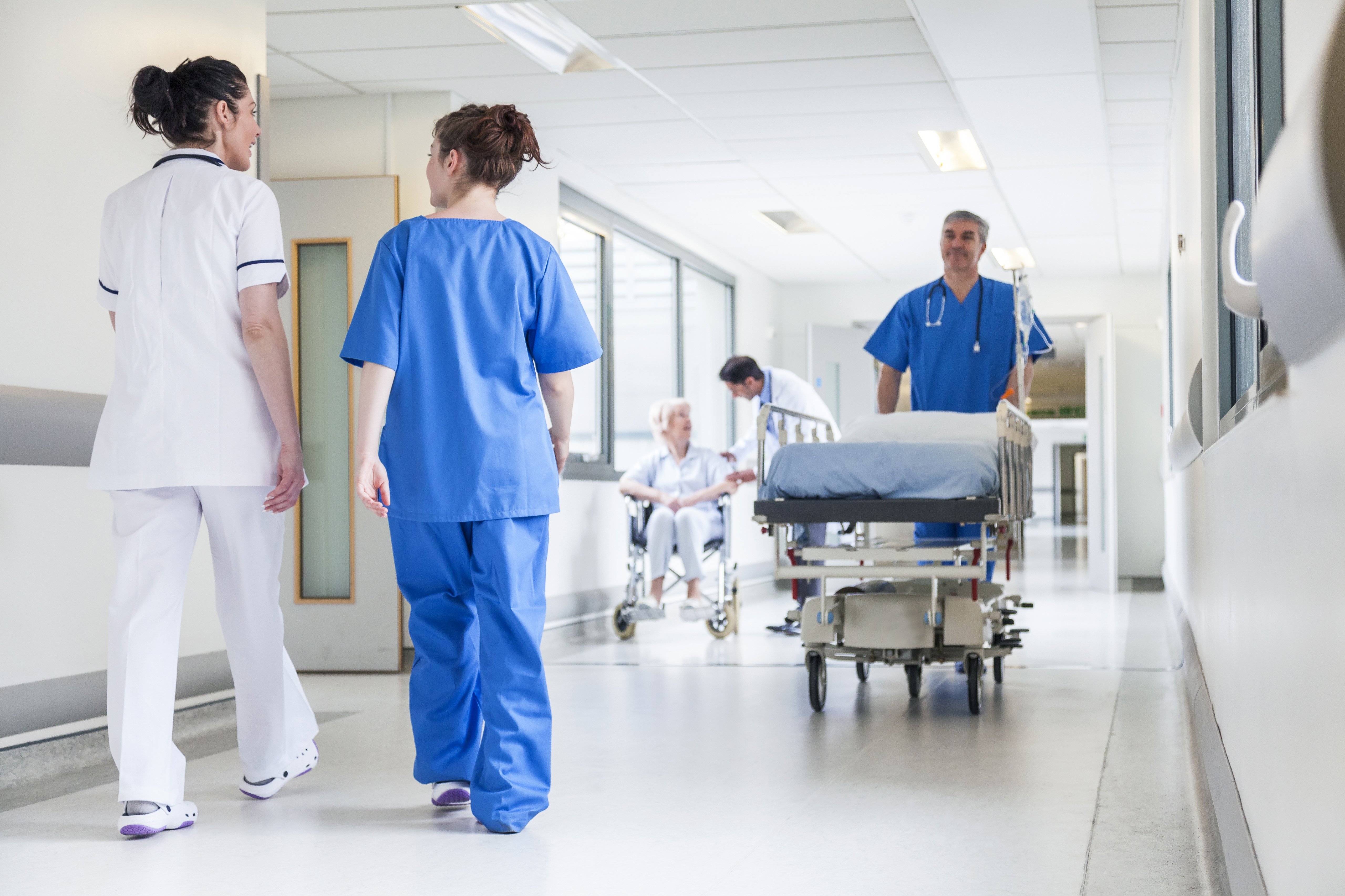 Hombre trasladando camilla en pasillo de hospital, rodeado de personal médico. | Imagen: Shutterstock