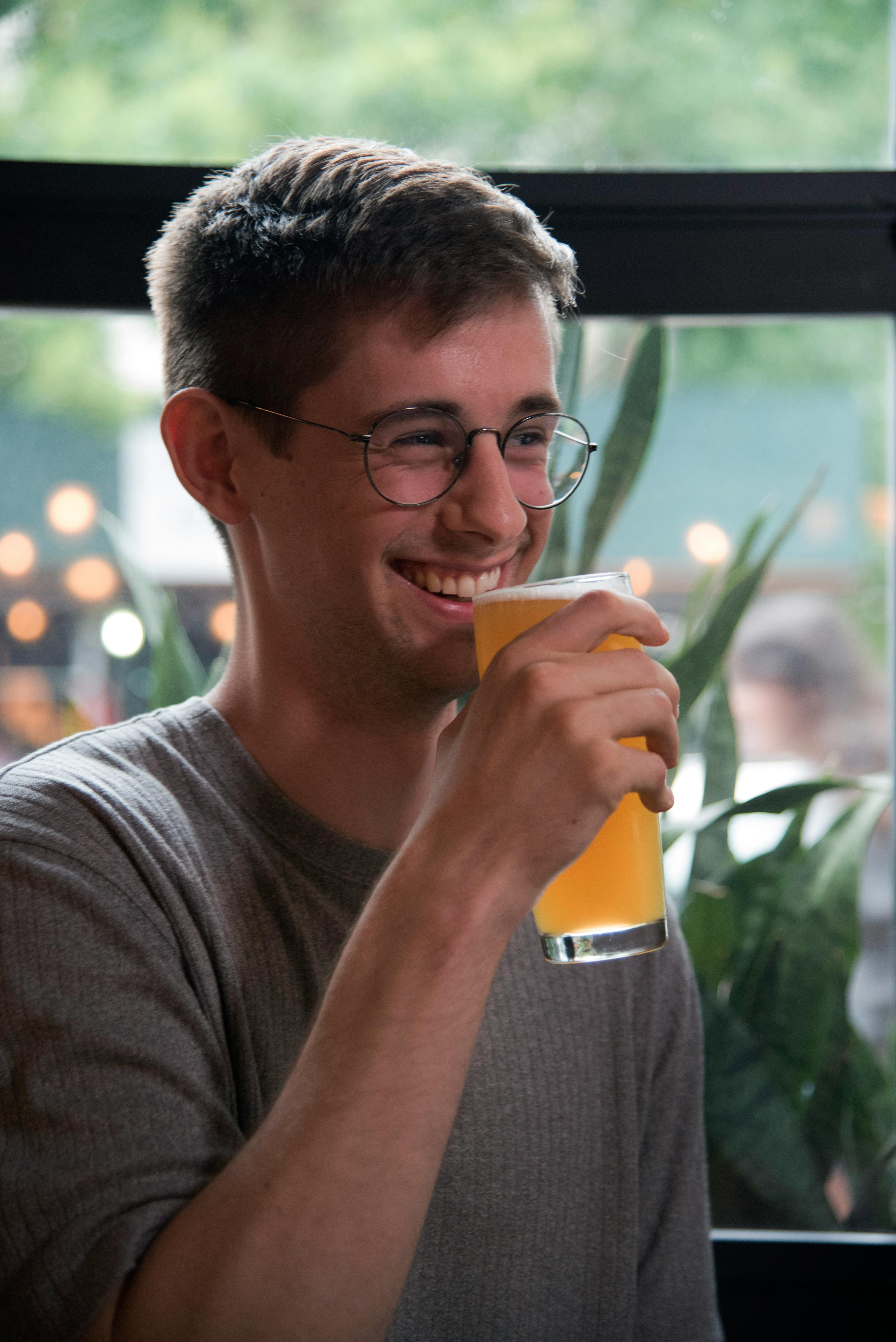 Un hombre tomando una bebida mientras ríe | Fuente: Pexels