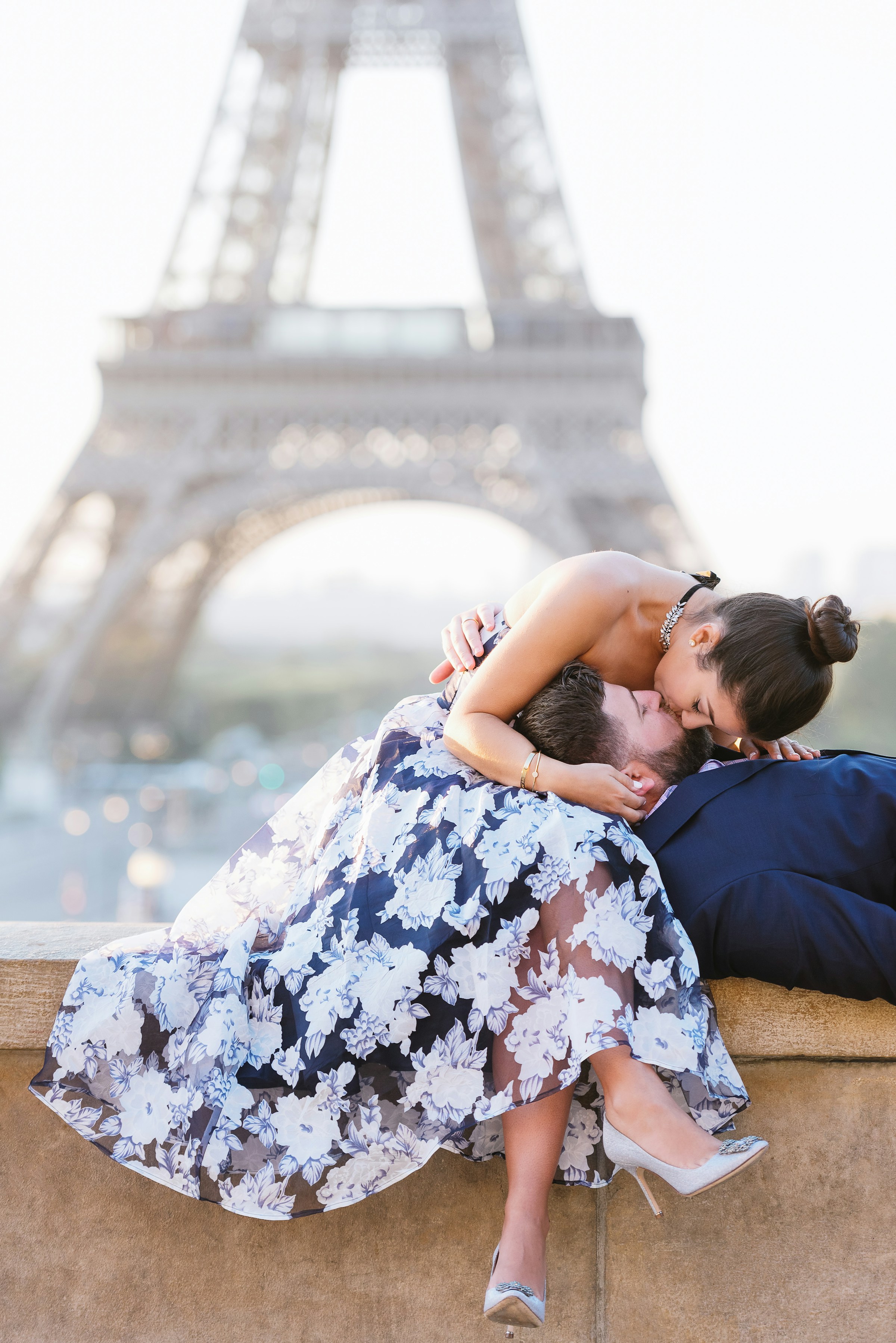 Una pareja besándose en una cornisa frente a la Torre Eiffel de París | Fuente: Unsplash