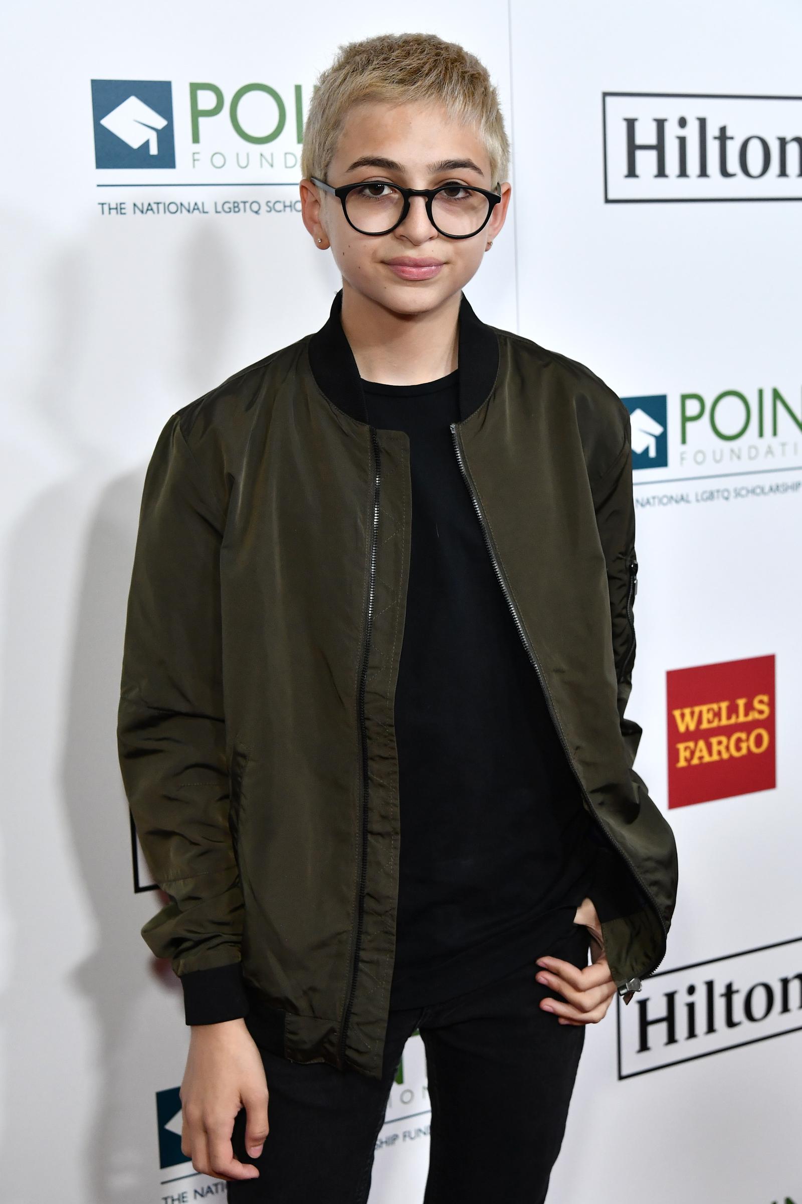 J.J. Totah asiste a la gala Point Honors en Los Ángeles, California, con una chaqueta bomber oscura sobre una camisa negra, pantalones negros y gafas redondas. El pelo corto y claro de Totah completa el look. | Fuente: Getty Images