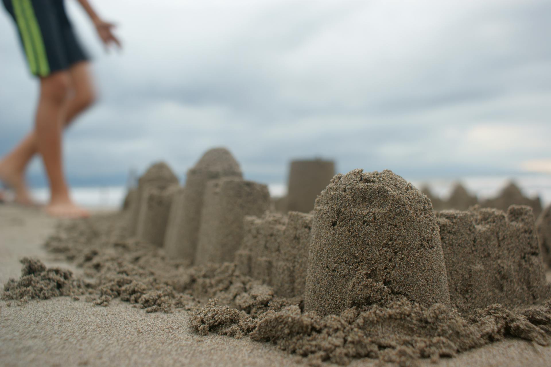 Un niño cerca de un castillo de arena | Fuente: Pexels