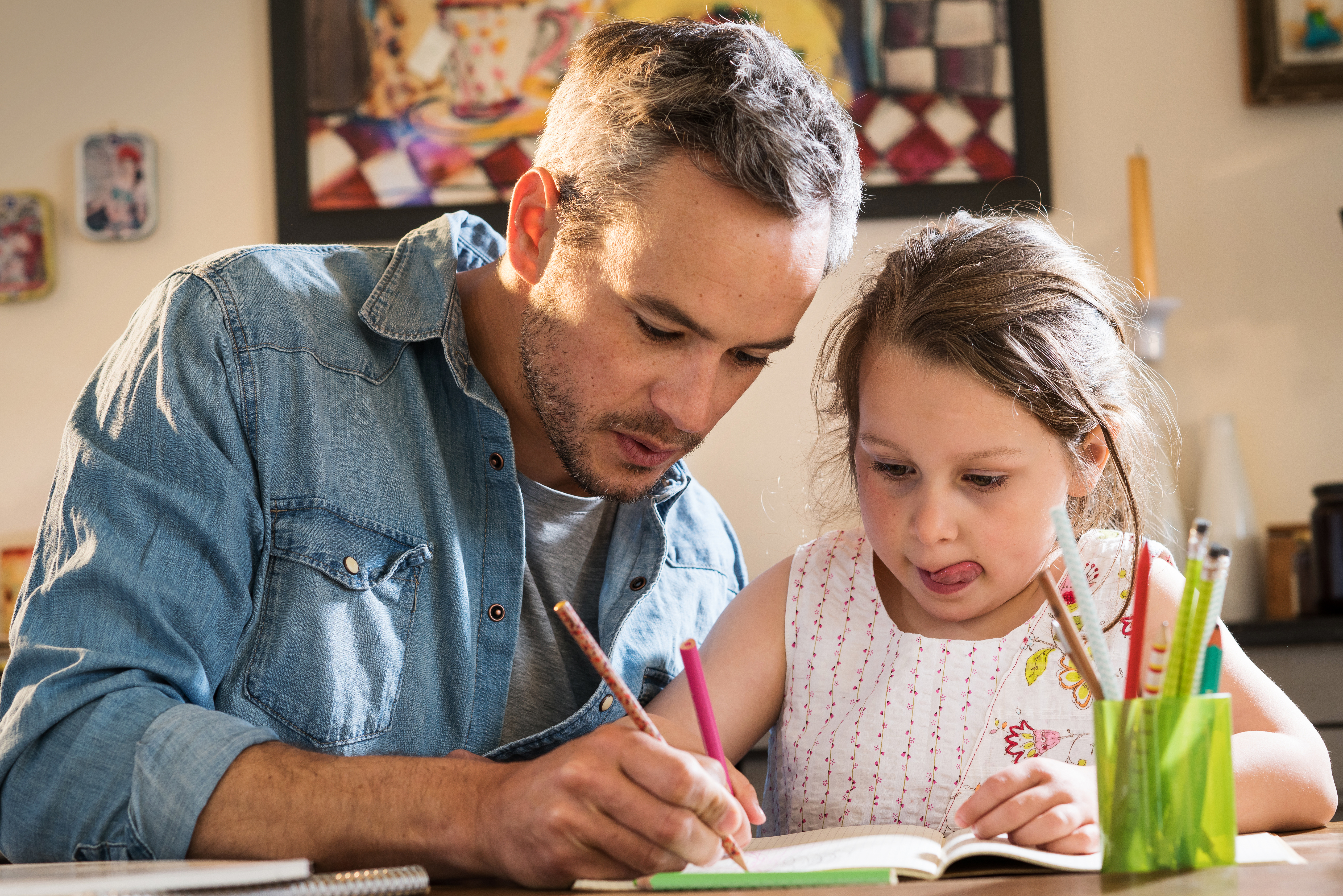 Un padre ayudando a su hija con los deberes | Fuente: Shutterstock