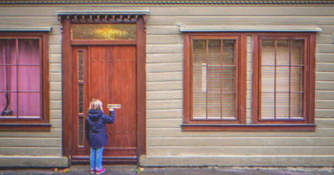 Una niña parada frente a la puerta de una casa. | Foto: Shutterstock