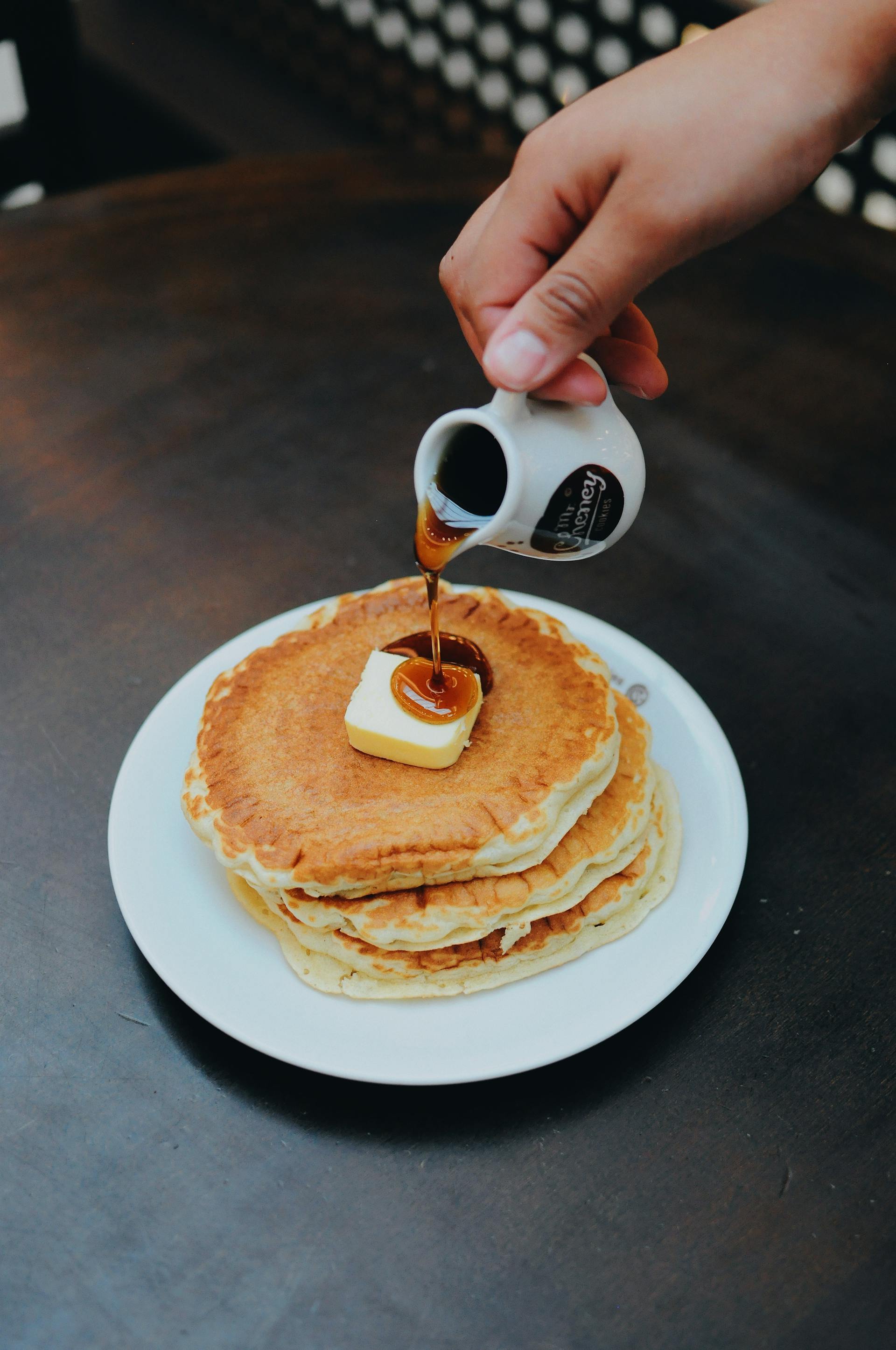 Una persona echando sirope en las tortitas | Fuente: Pexels