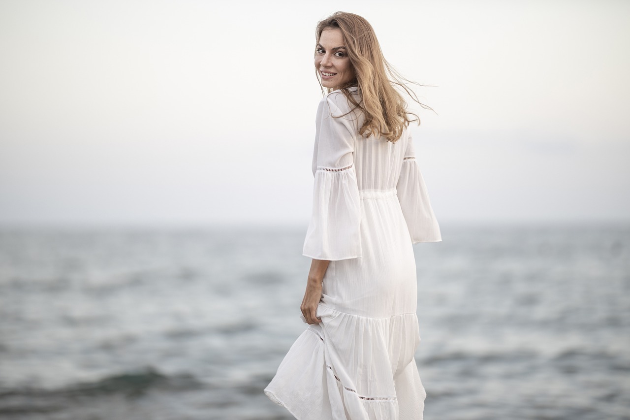 Una mujer sonriente con un vestido blanco | Fuente: Pixabay