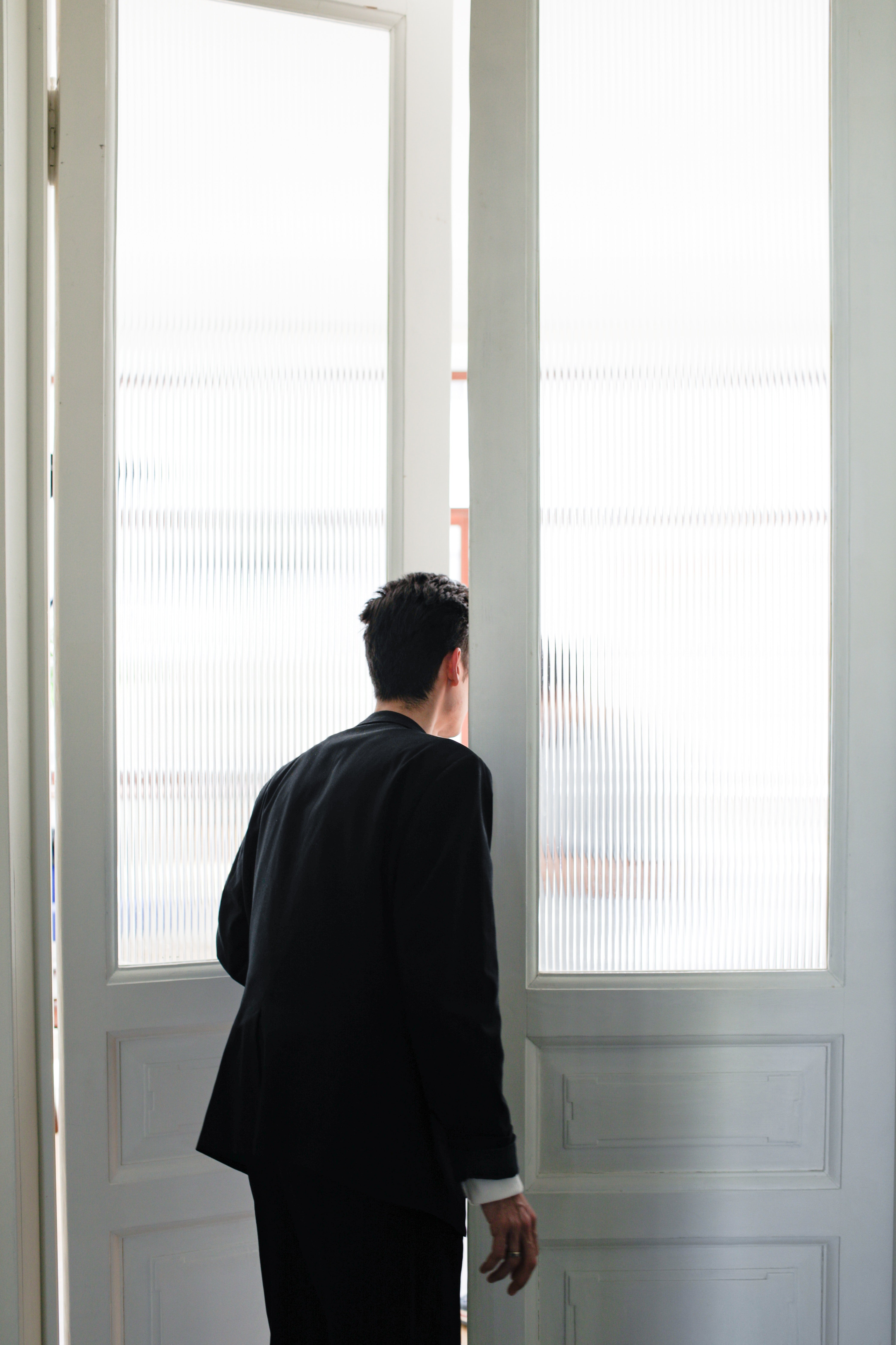 Hombre joven se asoma a la puerta de su casa. | Foto: Pexels