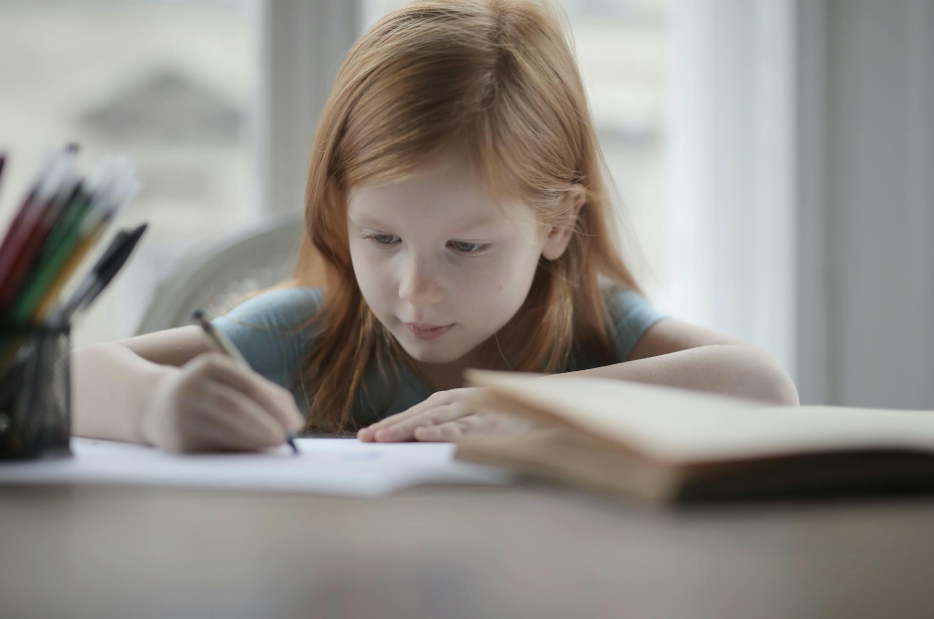 Una niña dibujando algo en un papel | Fuente: Pexels