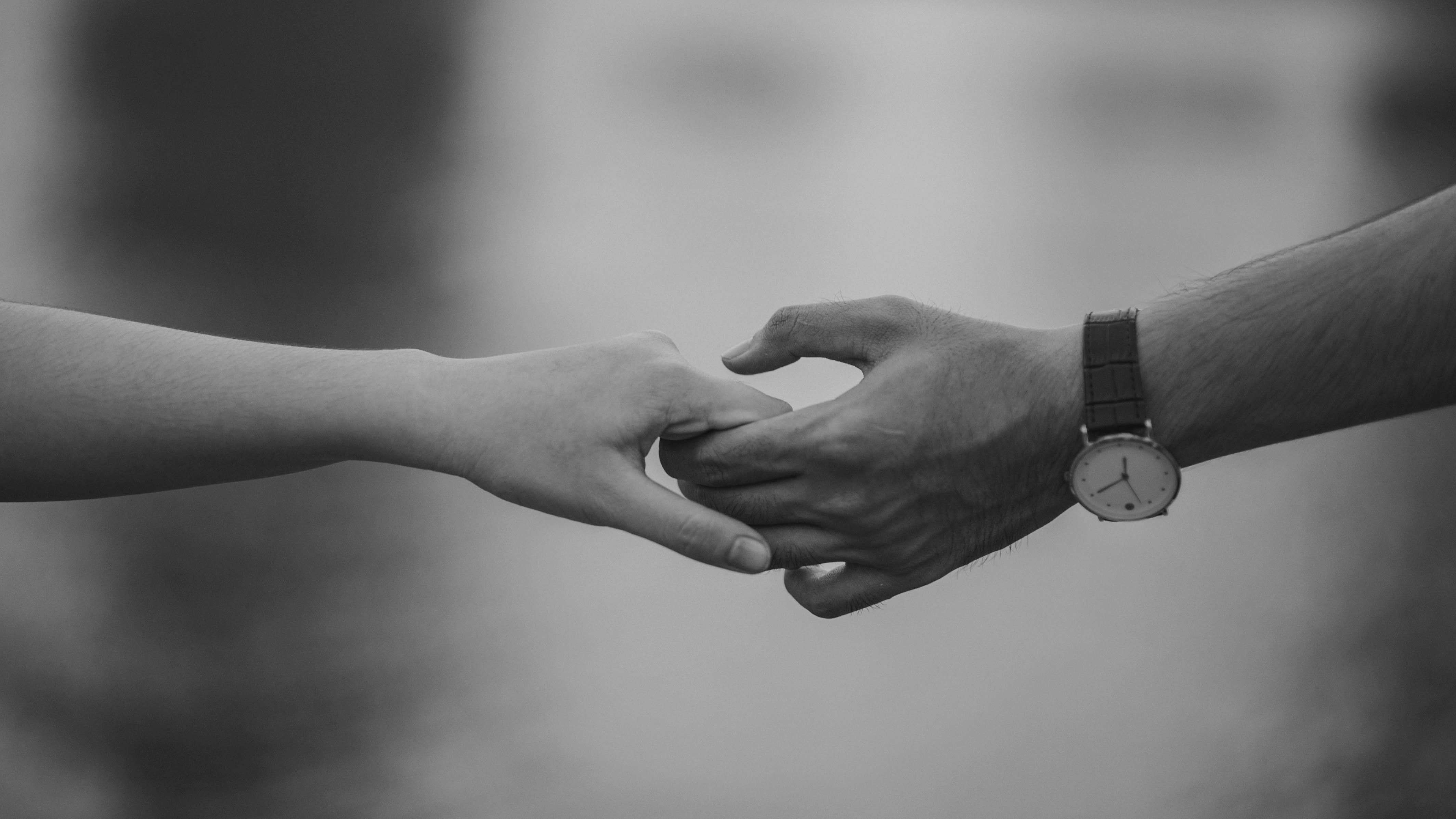 Un primer plano en blanco y negro de una pareja cogida de la mano | Foto: Pexels