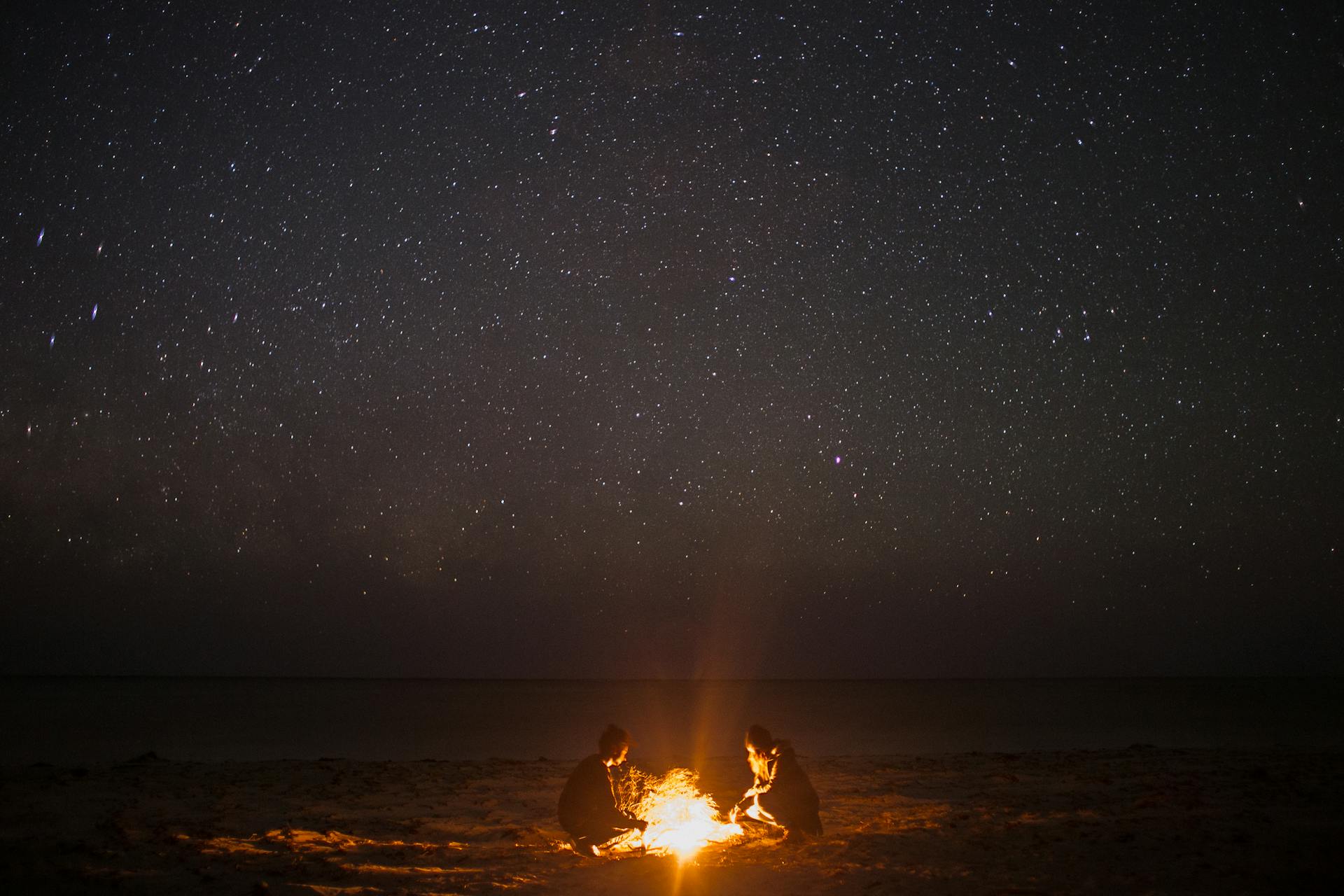 Gente cerca de una hoguera en una playa por la noche | Fuente: Pexels