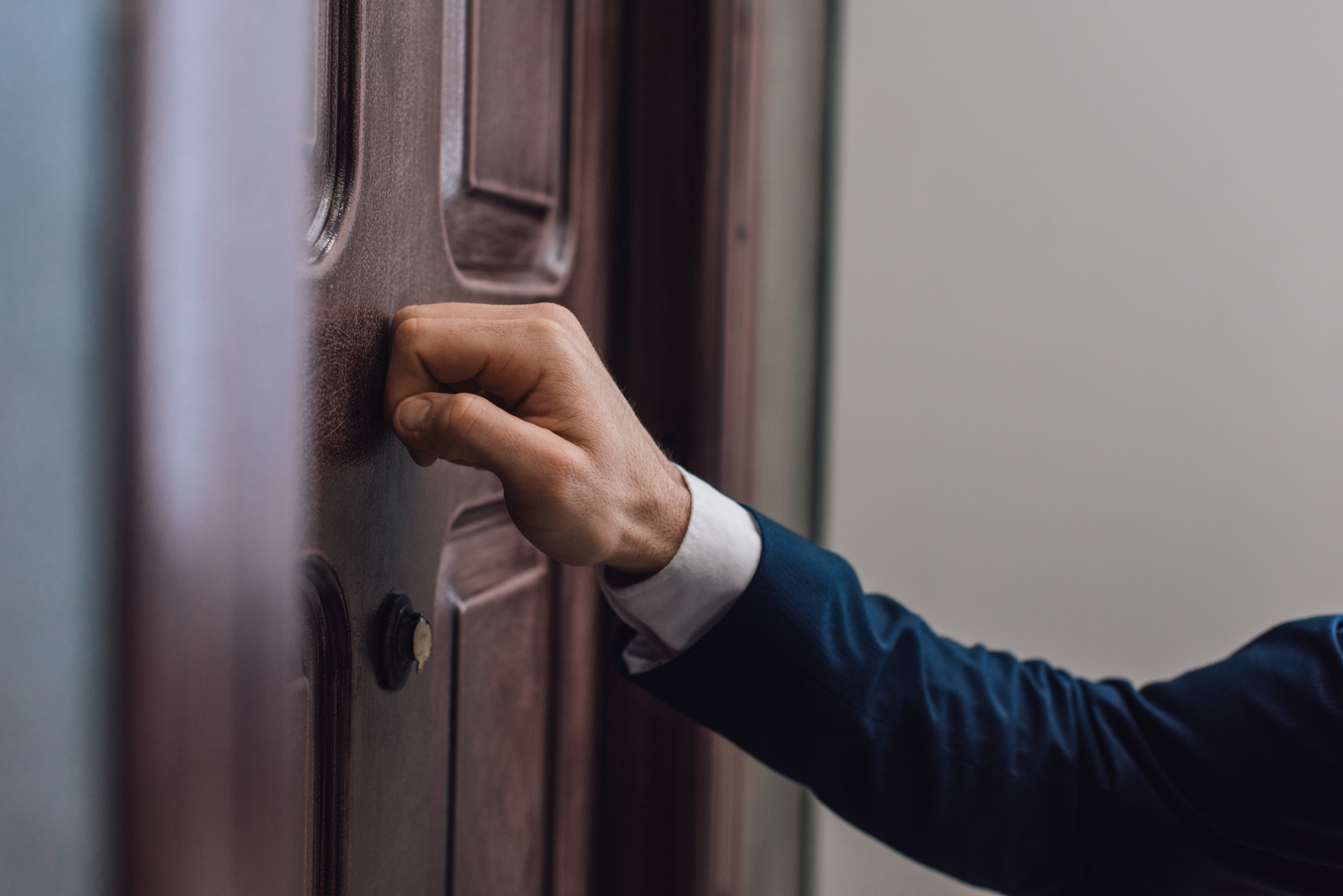 Vista recortada de un hombre llamando a la puerta con la mano. | Fuente: Shutterstock