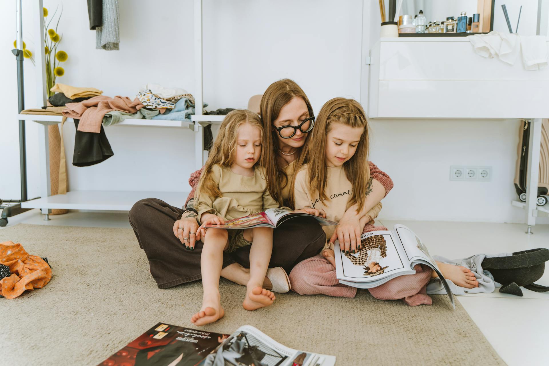 Mujer hojeando revistas con sus hijas pequeñas | Fuente: Pexels