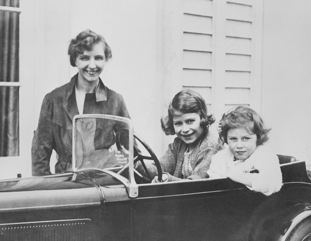 Elizabeth II (futura reina de Gran Bretaña) y su hermana, la princesa Margaret, jugando en un automóvil en miniatura junto a su institutriz, Marion Crawford. Año 1930. | Foto: Getty Images
