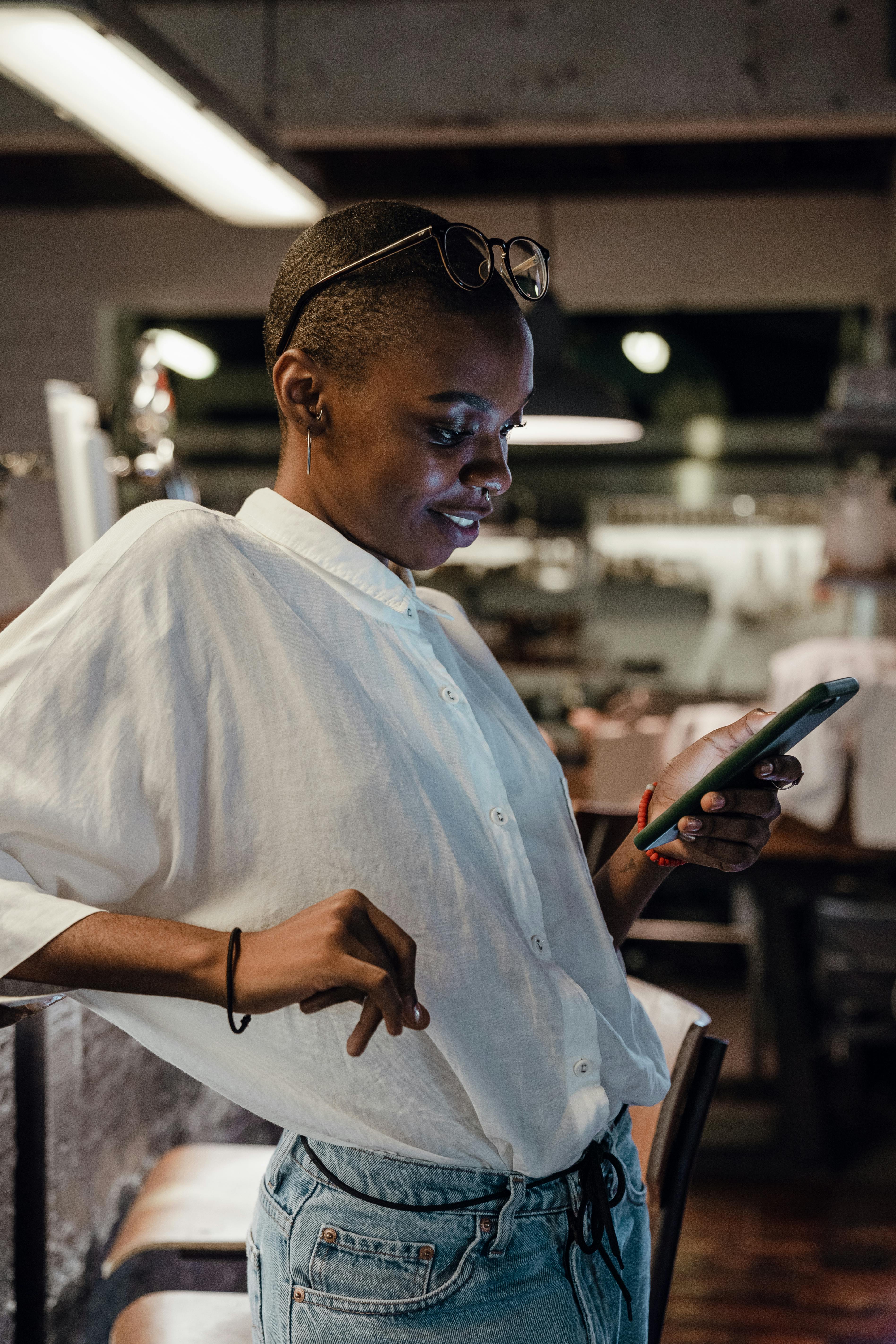 Una mujer feliz mirando su teléfono en una cafetería | Fuente: Pexels