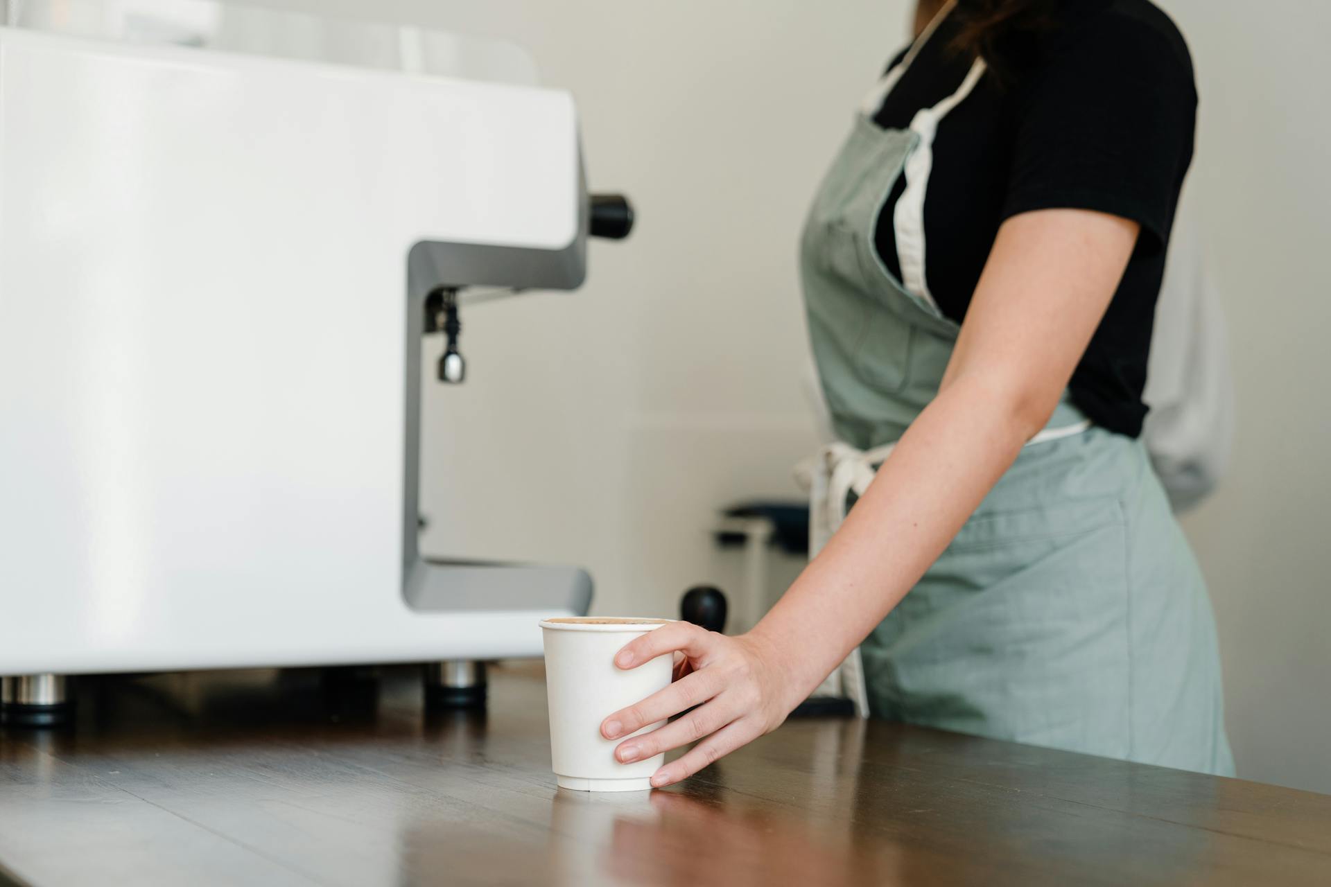 Primer plano recortado de una camarera sujetando una taza de café | Fuente: Pexels