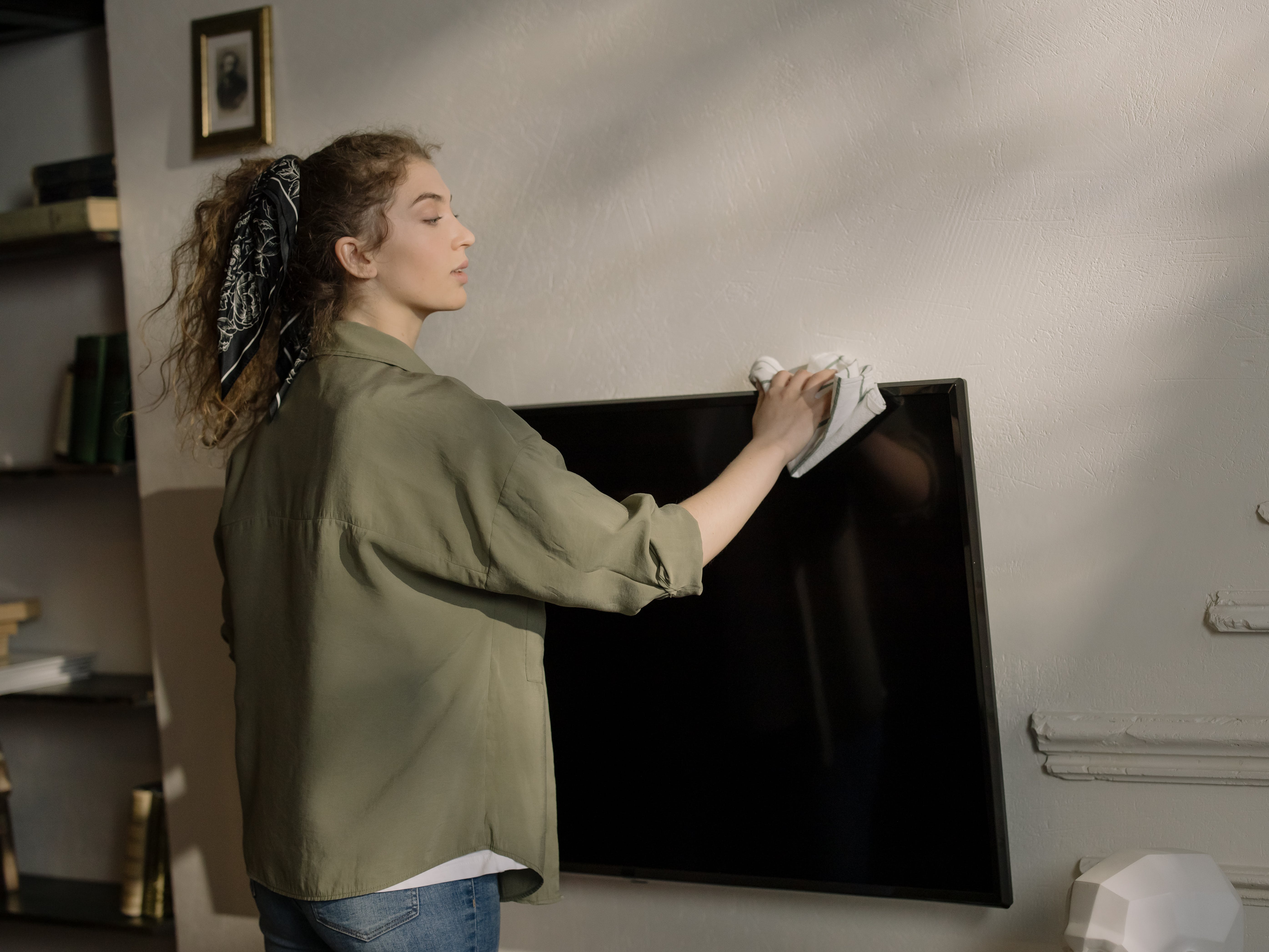 Una mujer de pie sujetando un televisor de pantalla plana. | Fuente: Pexels