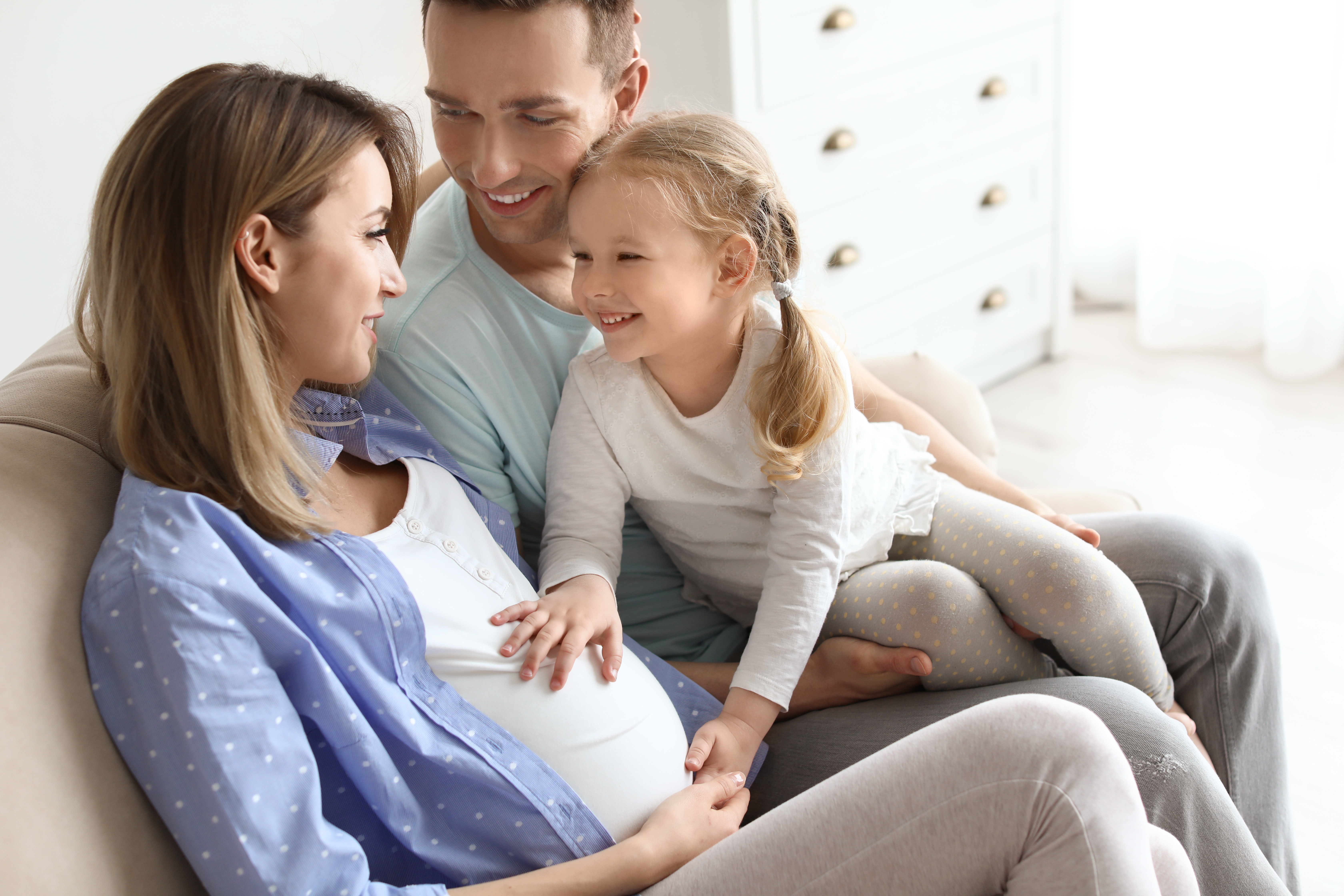 Una mujer embarazada con su marido y su hija pequeña en casa | Fuente: Shutterstock