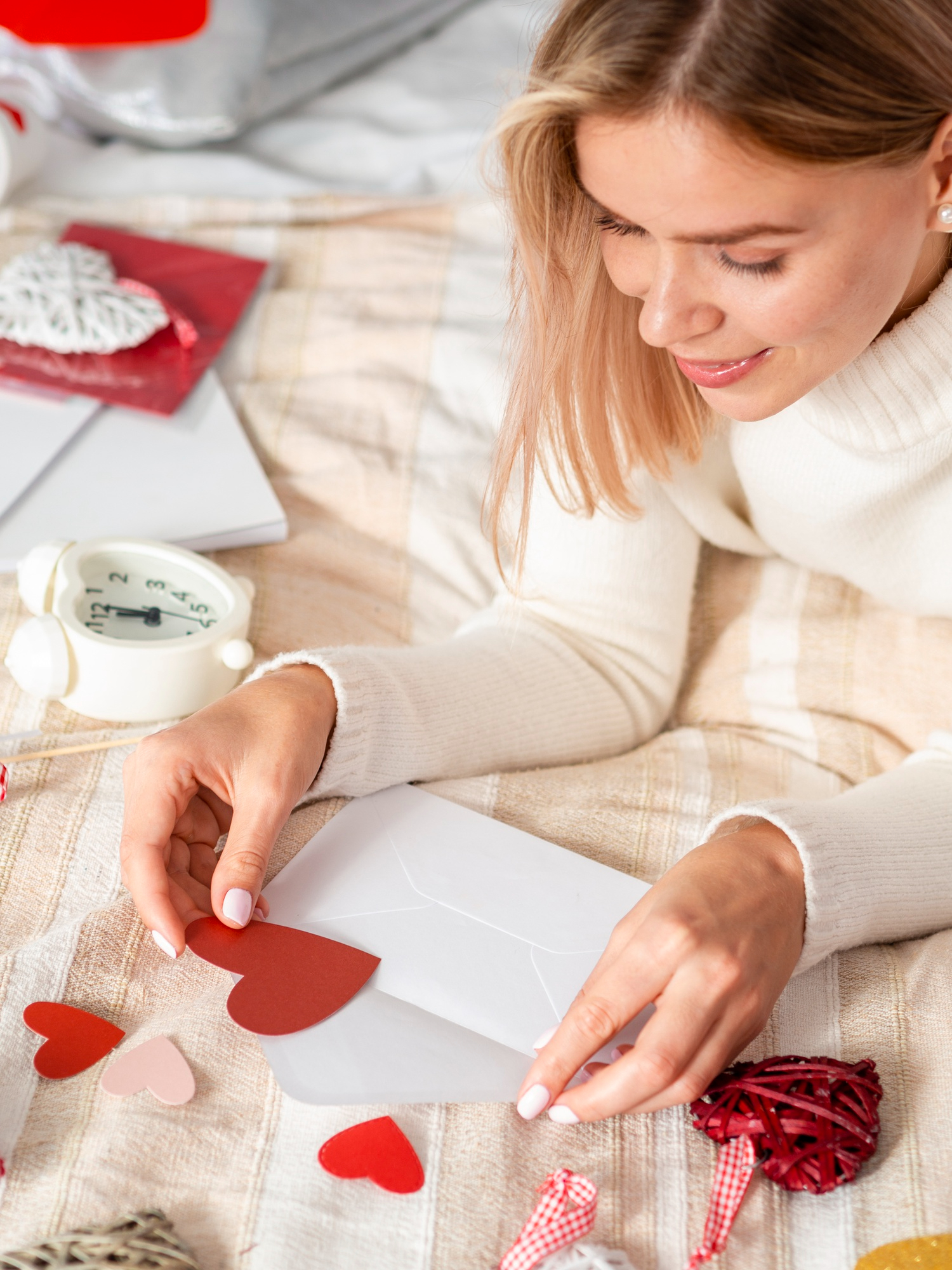 Una mujer colocando un papel con forma de corazón dentro de un sobre | Fuente: Freepik