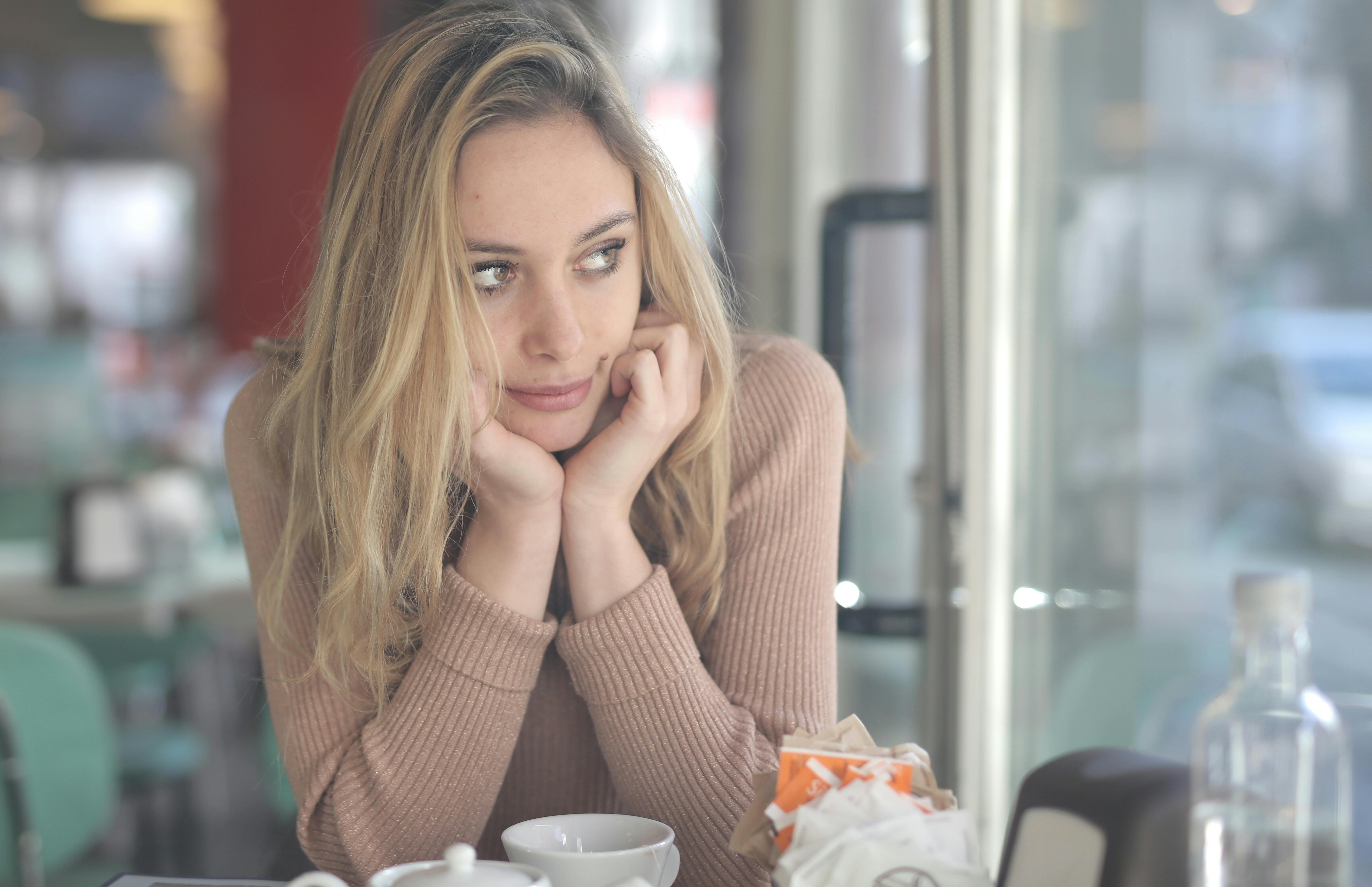 Mujer con jersey marrón sentada a la mesa | Foto: Pexels