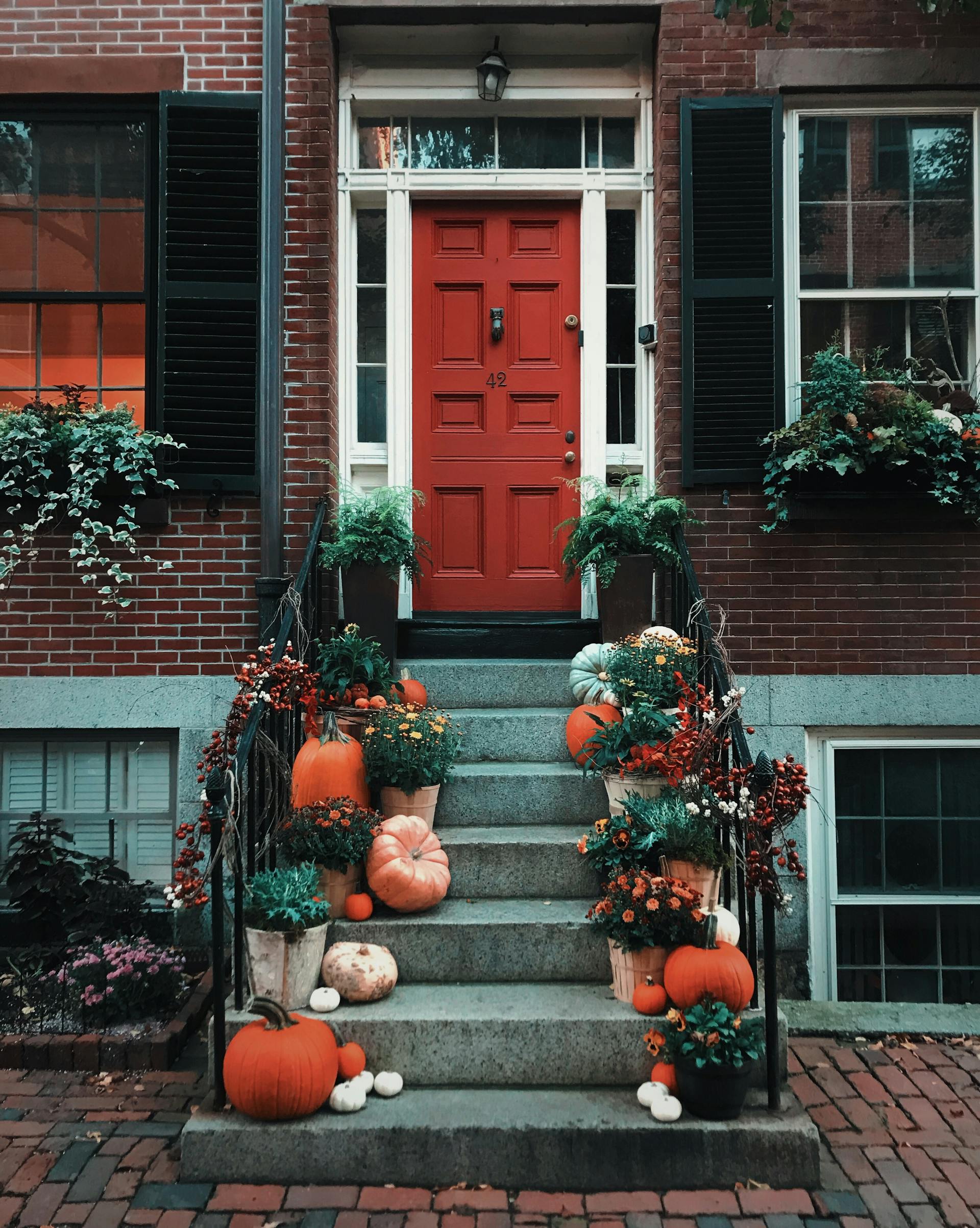 Calabazas en la escalera delante de una puerta | Fuente: Pexels