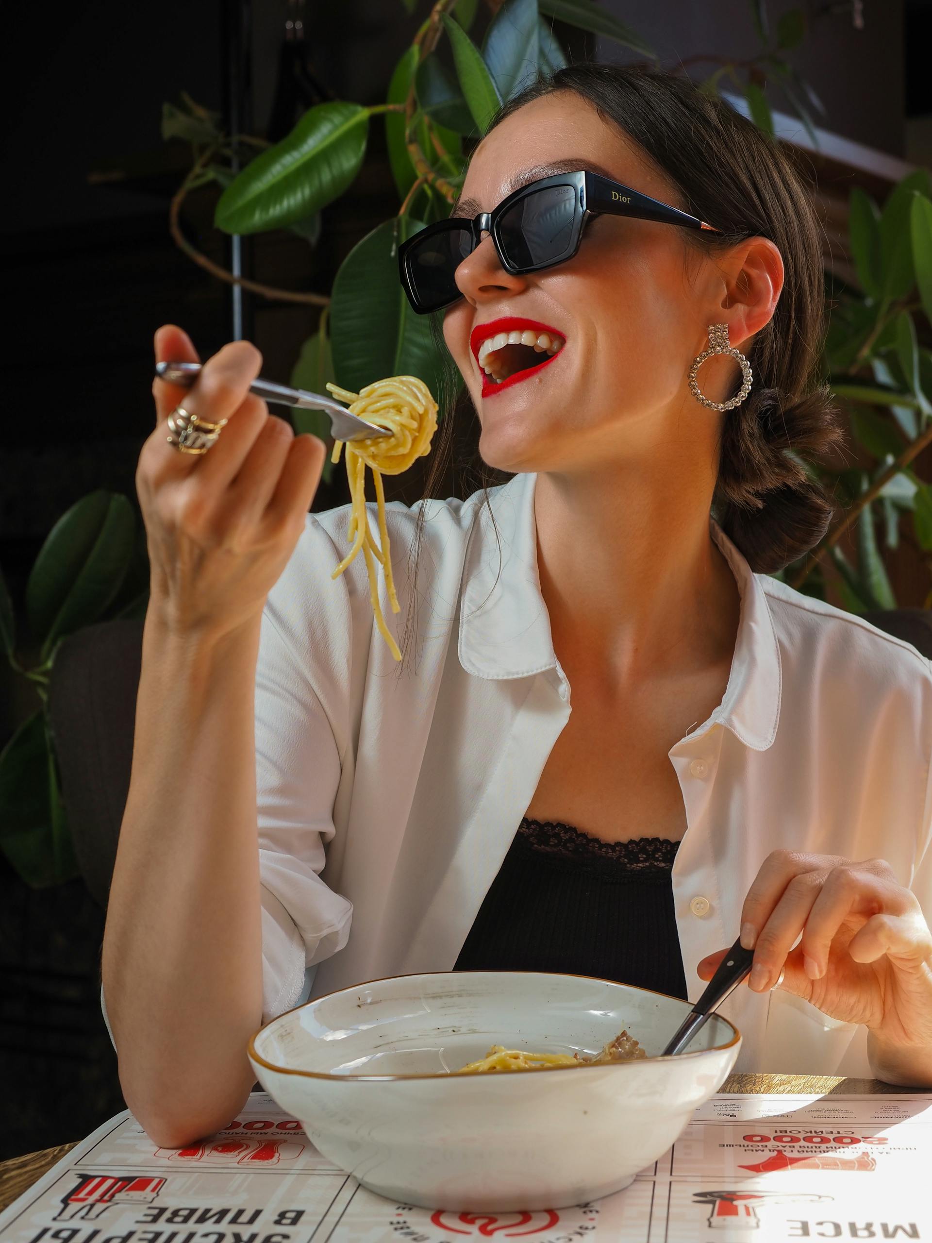Mujer sonriente comiendo en un restaurante | Fuente: Pexels