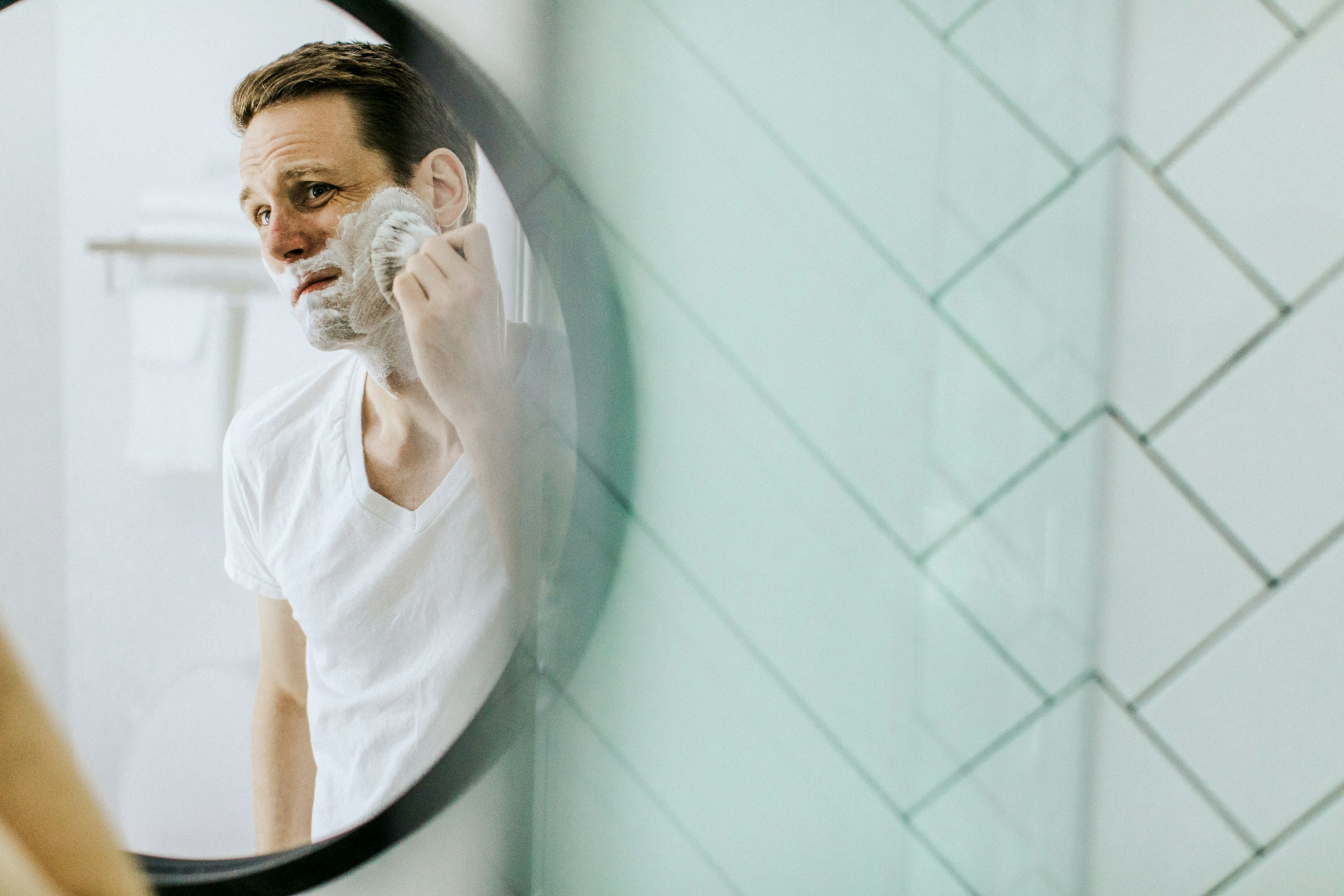 Un hombre afeitándose en un espejo | Fuente: Unsplash