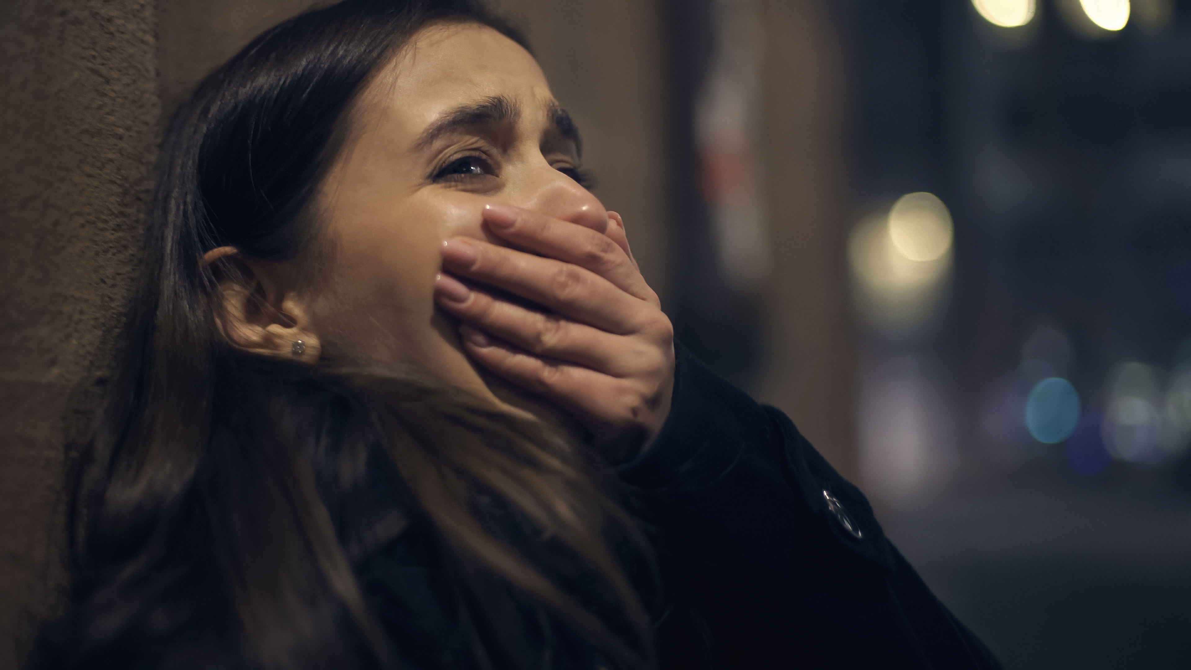 Una mujer asustada llora con la mano tapándose la boca | Fuente: Shutterstock